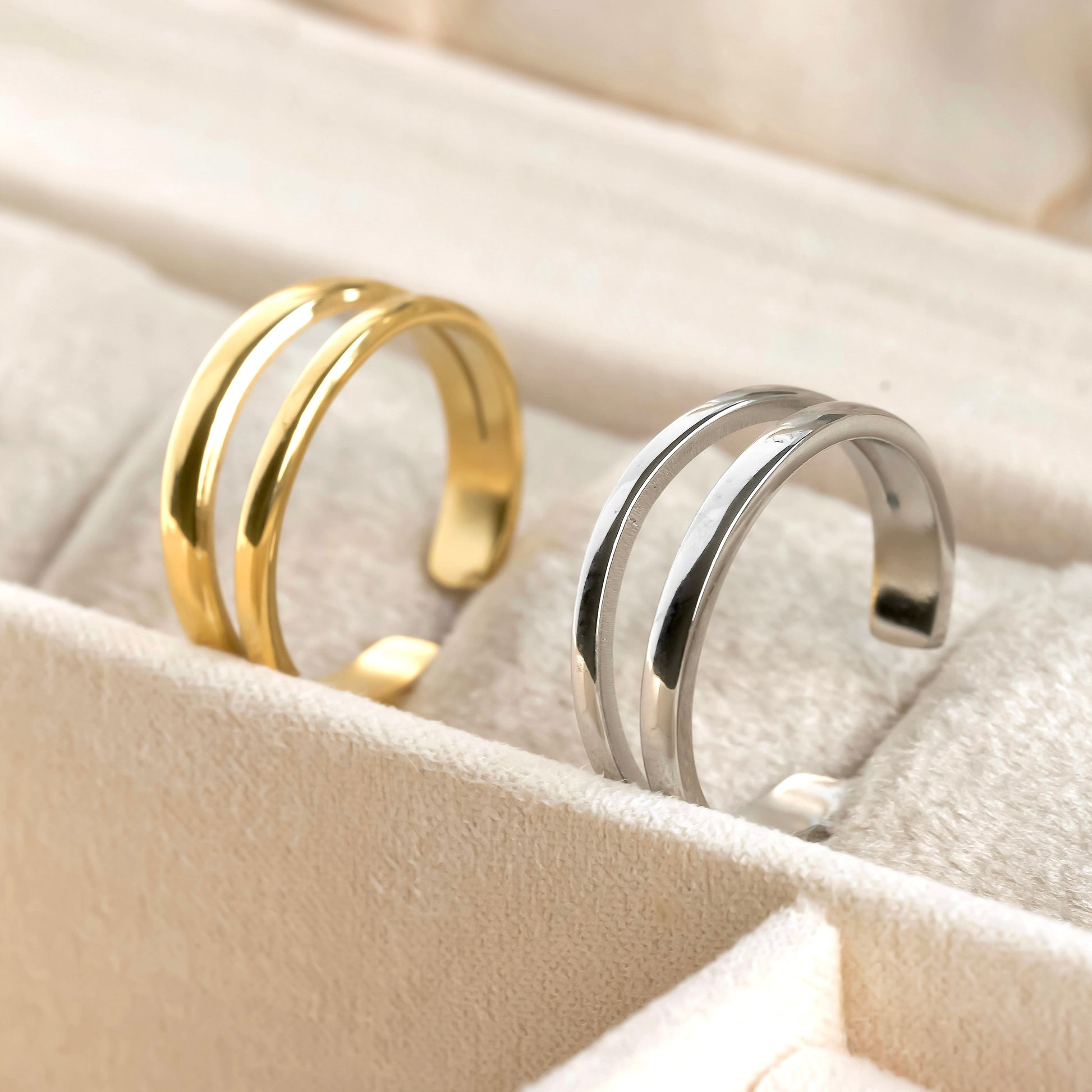 Gold and silver duo rings on a soft beige surface