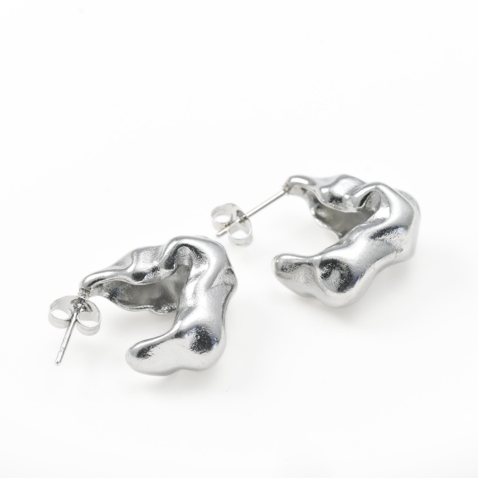 silver figure earrings on a white surface