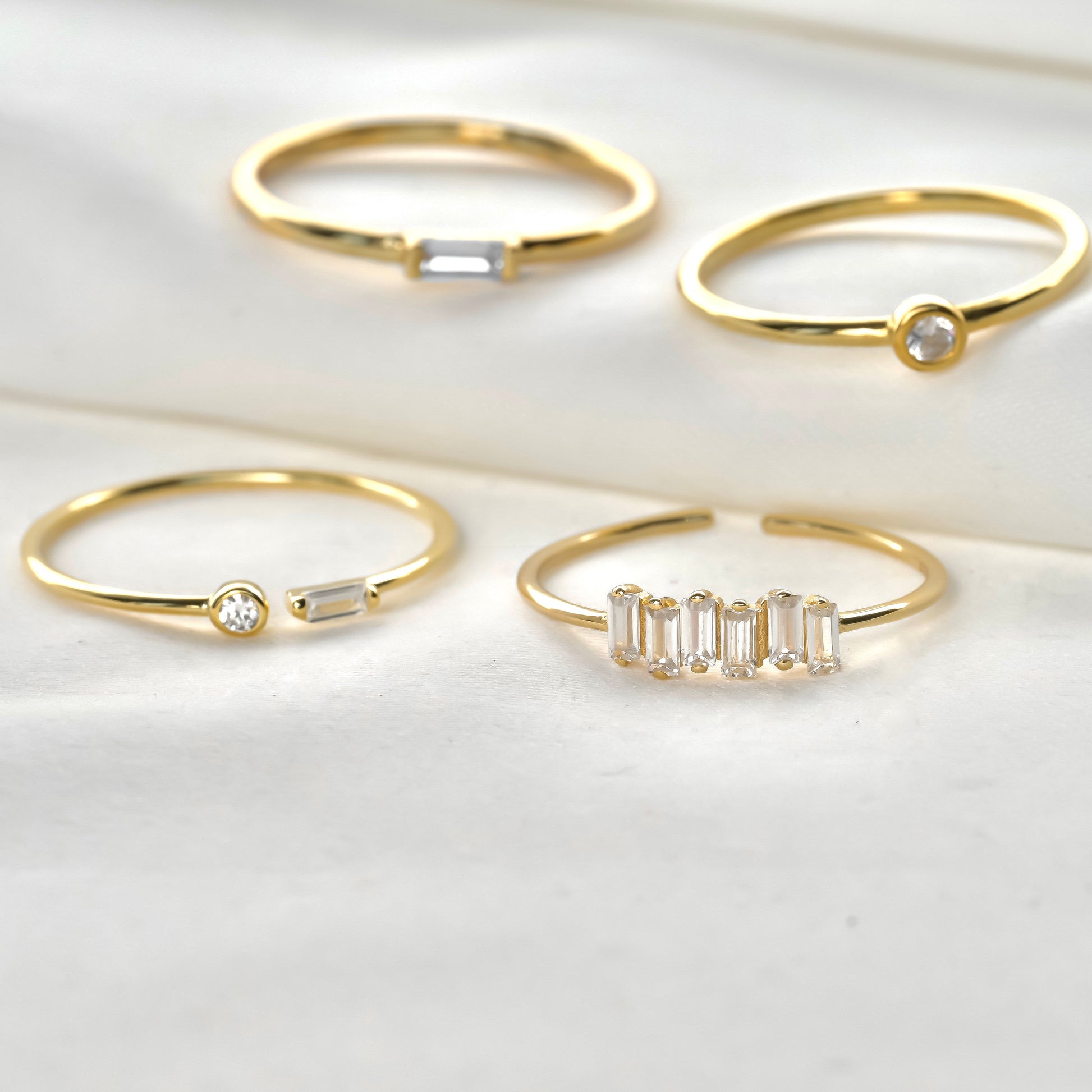 Close-up view of slim gold ringset with white gemstones on a light background