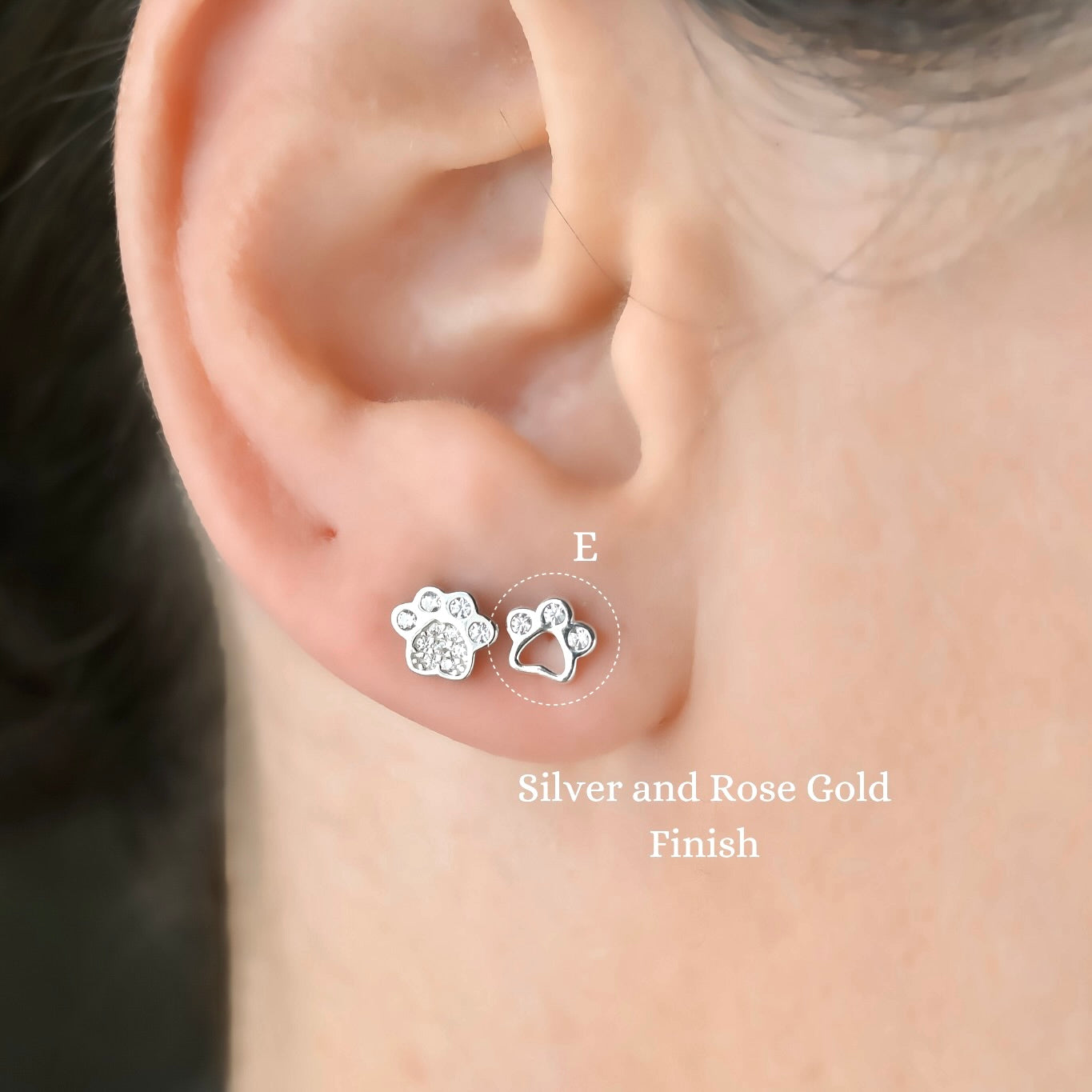 Full solid silver and cutout paw print stud earrings worn on an ear with a close-up view.