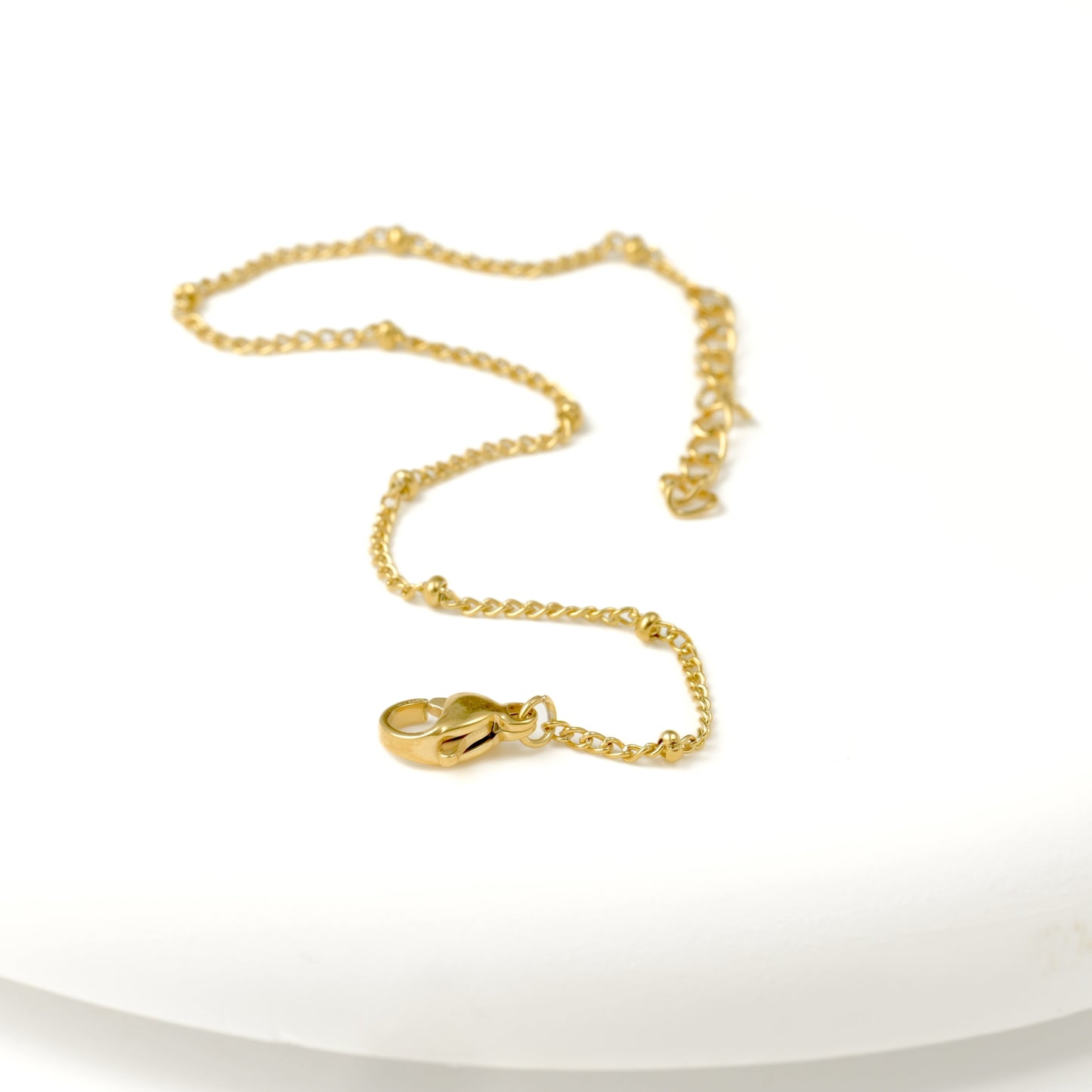 beaded curb chain bracelet with a lobster clasp and extender on a white background