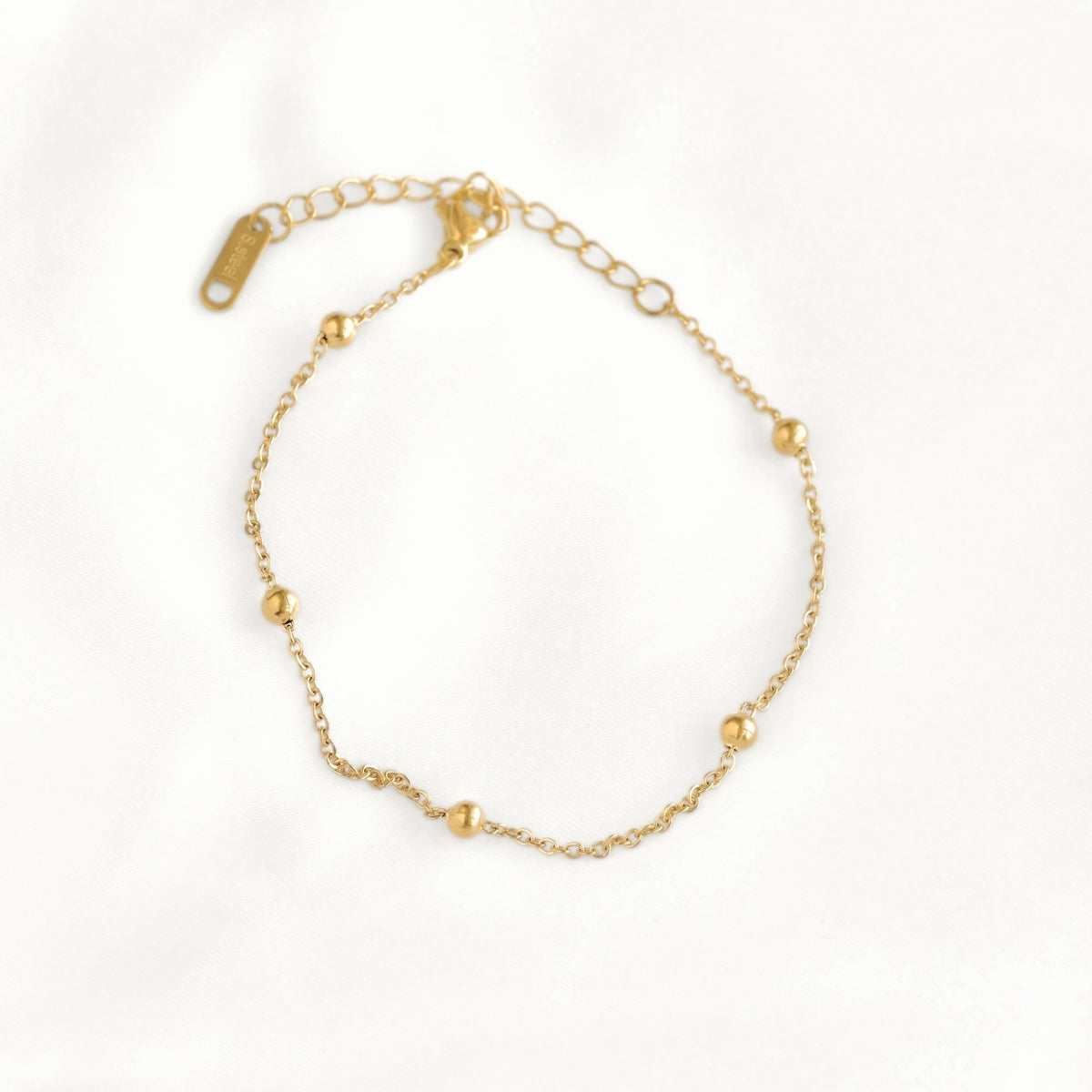 A delicate gold chain bracelet with small polished bead accents and an adjustable lobster clasp, displayed on a clean white background.