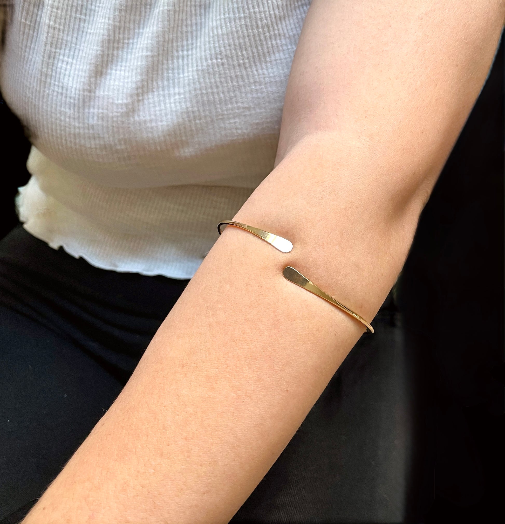 Gold forearm wrap bracelet on a person with a blurred background