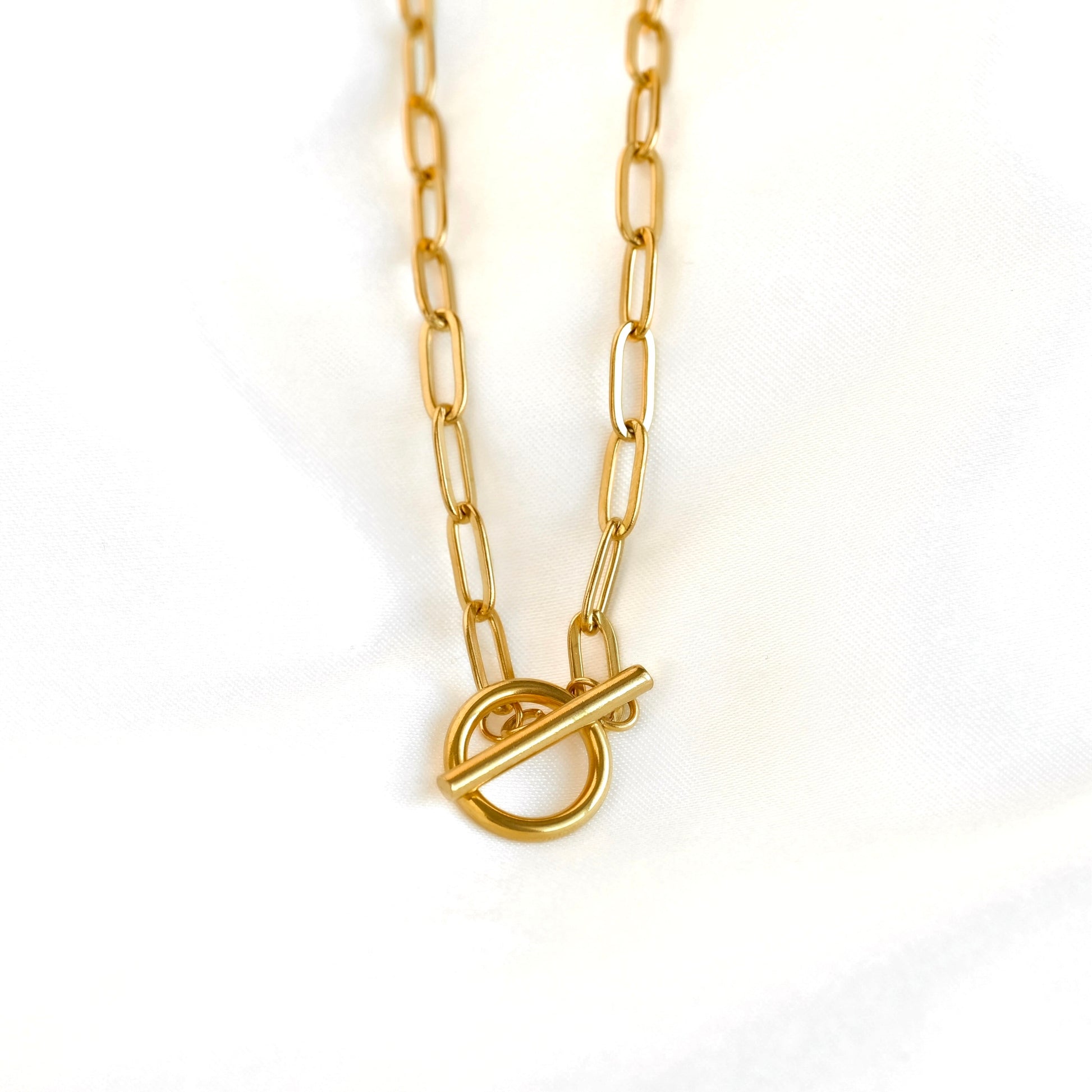 A gold paperclip chain necklace with a toggle ring clasp, photographed against a clean white background.