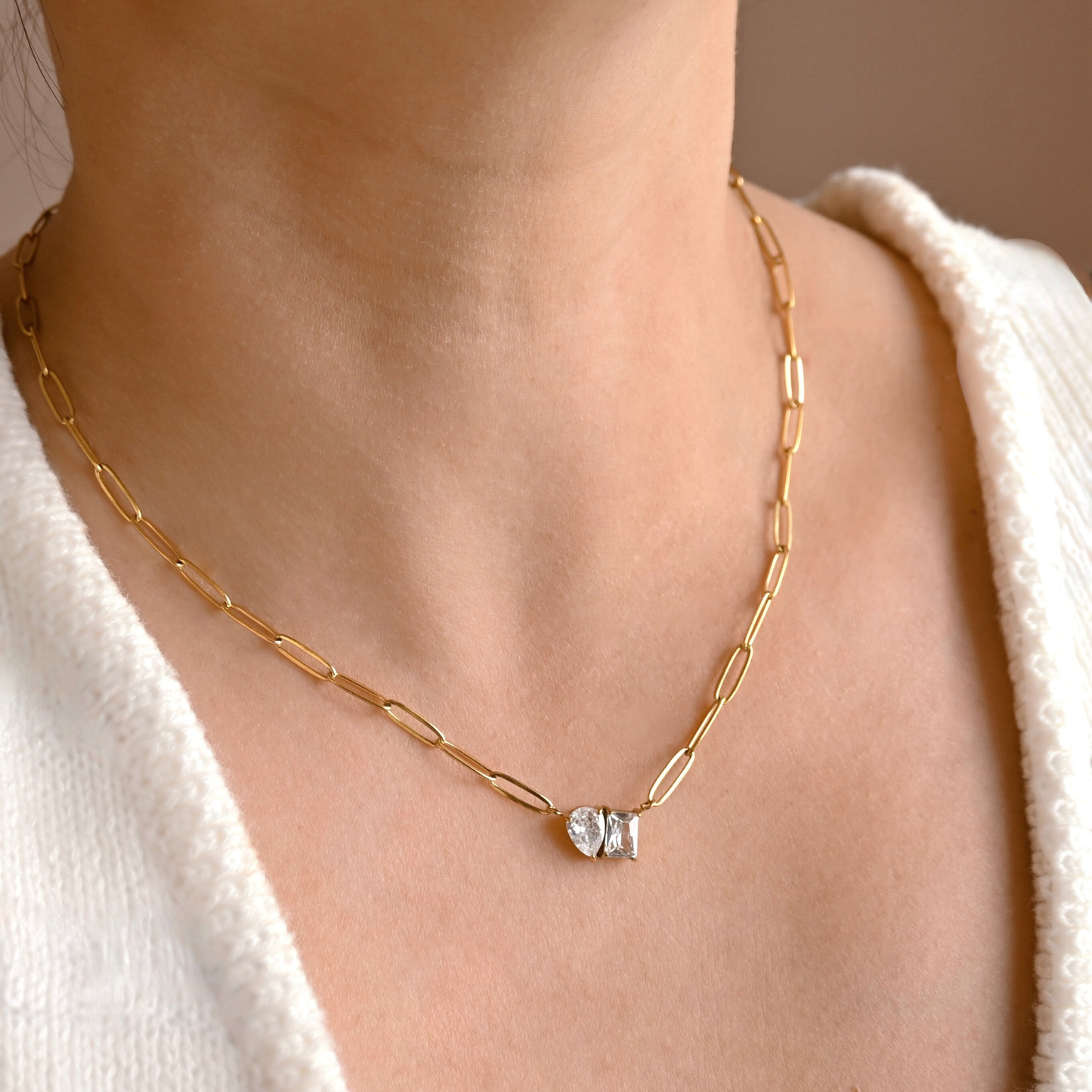 Gold chain necklace with a  toi et moi diamond pendant on a person wearing a white sweater.