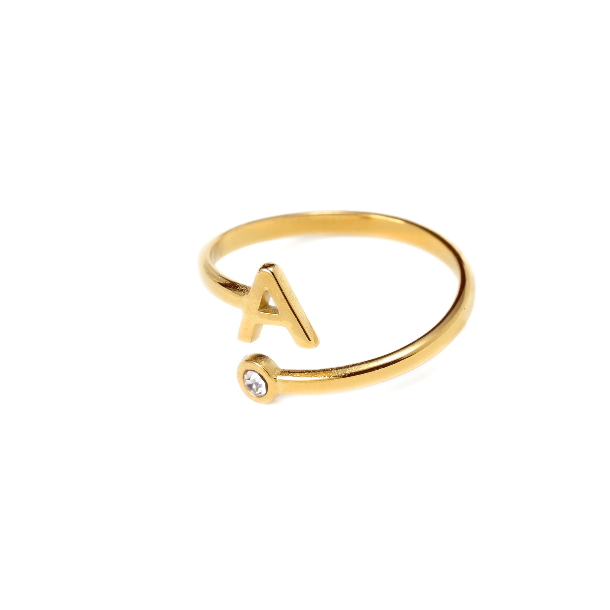 Gold ring with letter 'A' and small gemstone on a white background
