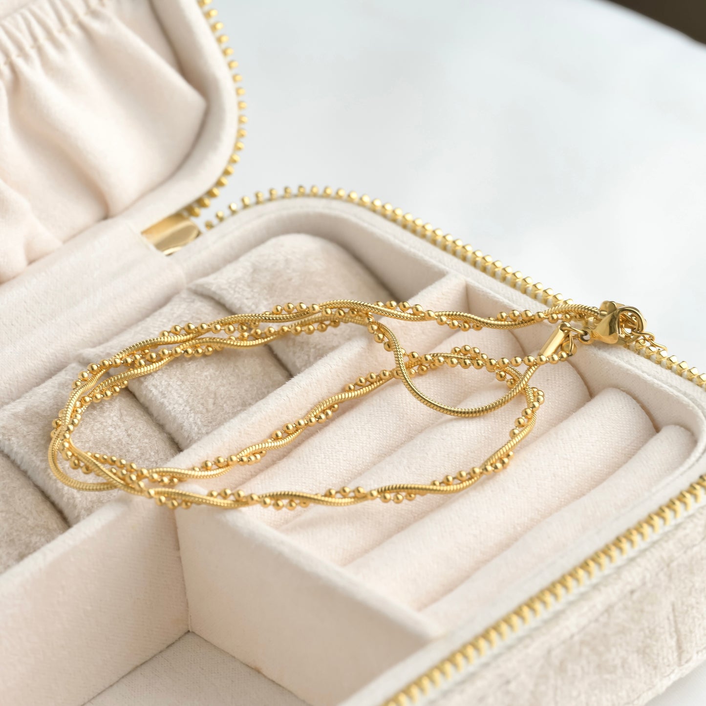Gold necklace in an open jewelry box on a light background