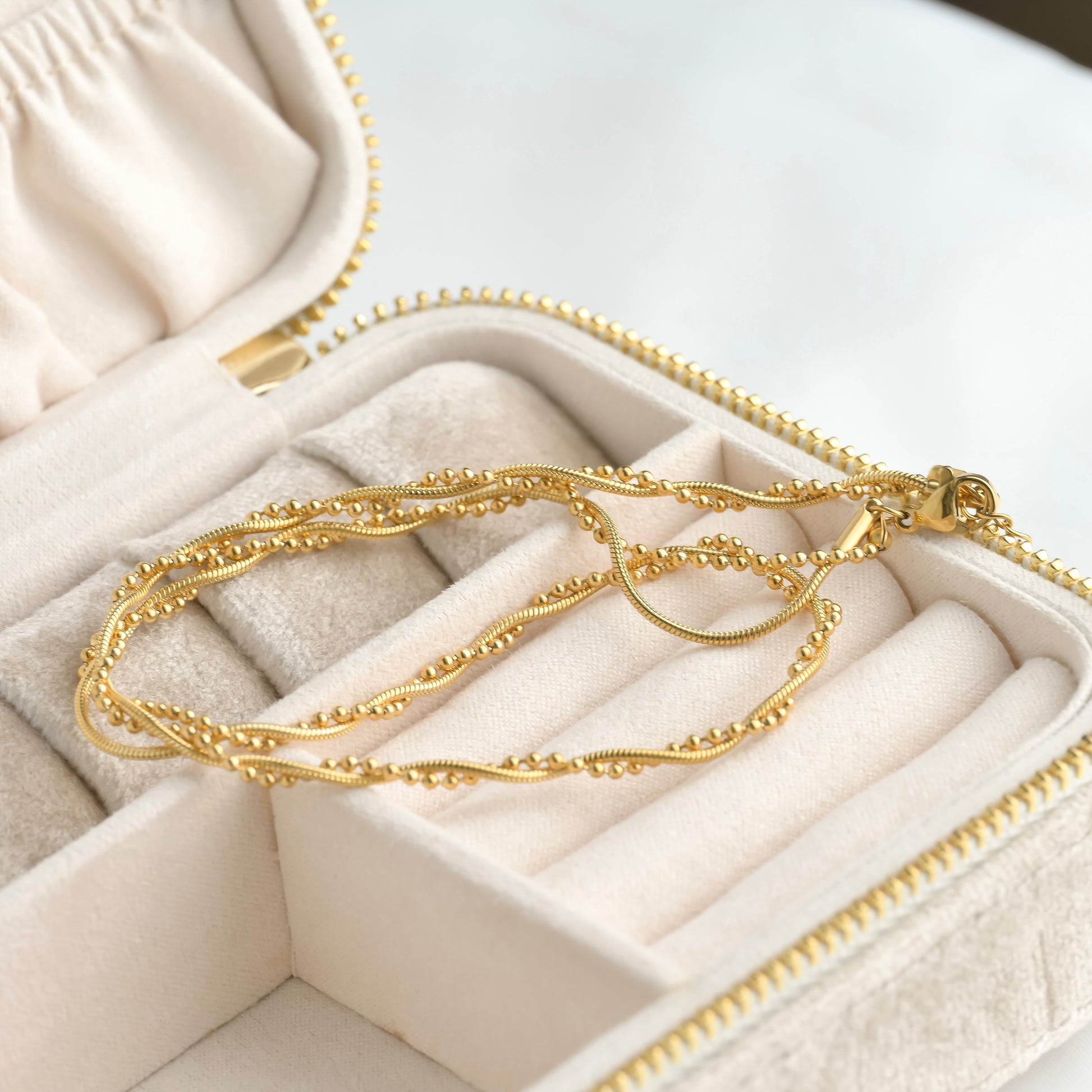 Gold necklace in an open jewelry box on a light background