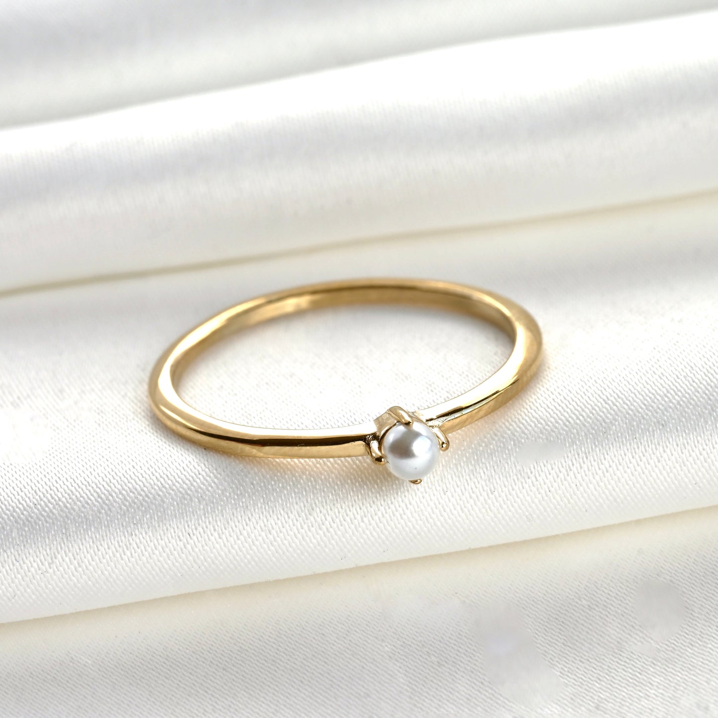 Gold ring with a pearl on a white fabric background