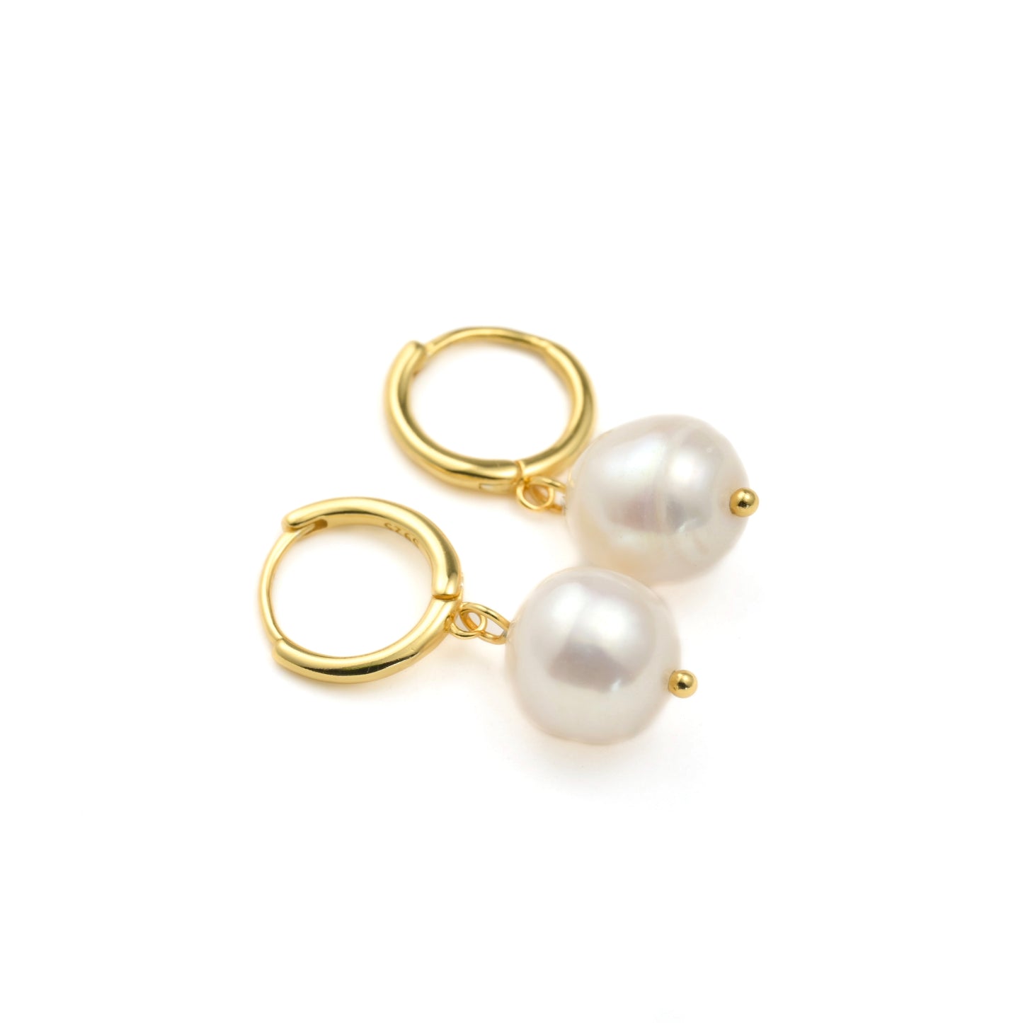 Gold huggie hoop earrings with white organic pearls drops on a white background