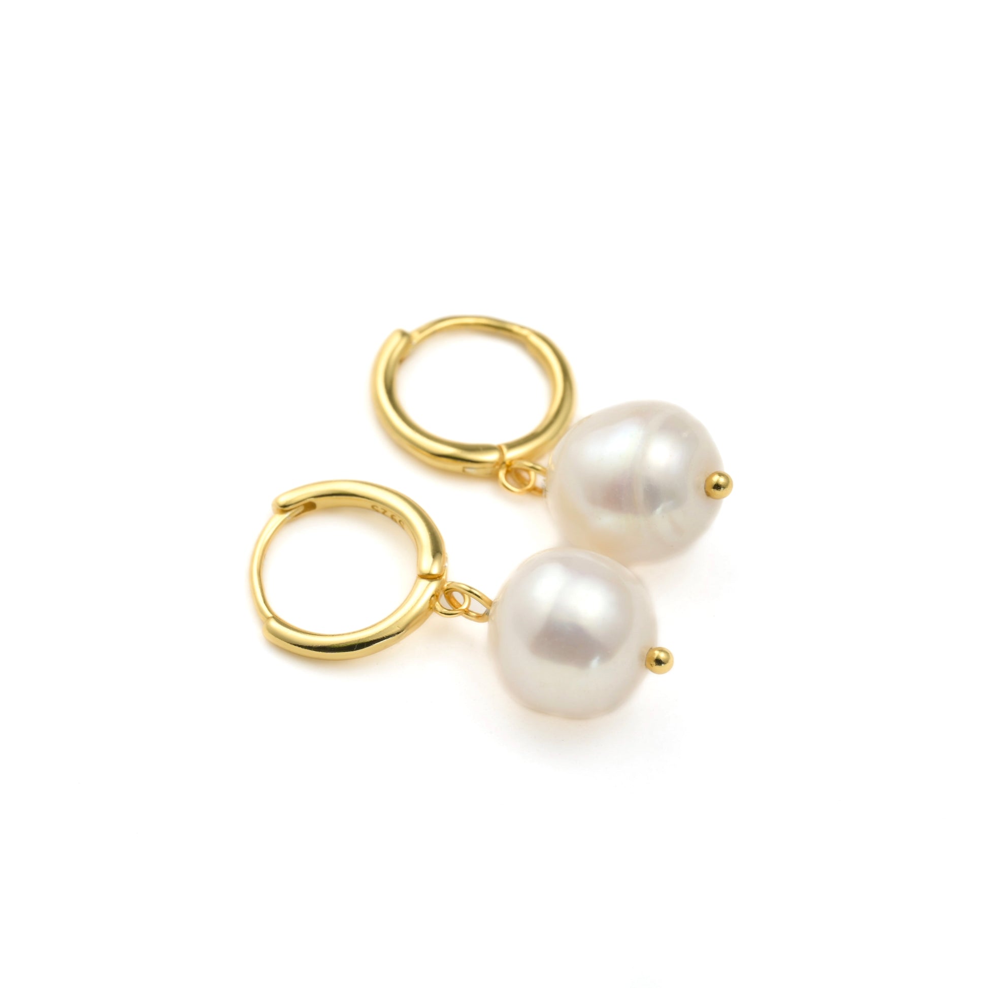 Gold huggie hoop earrings with white organic pearls drops on a white background