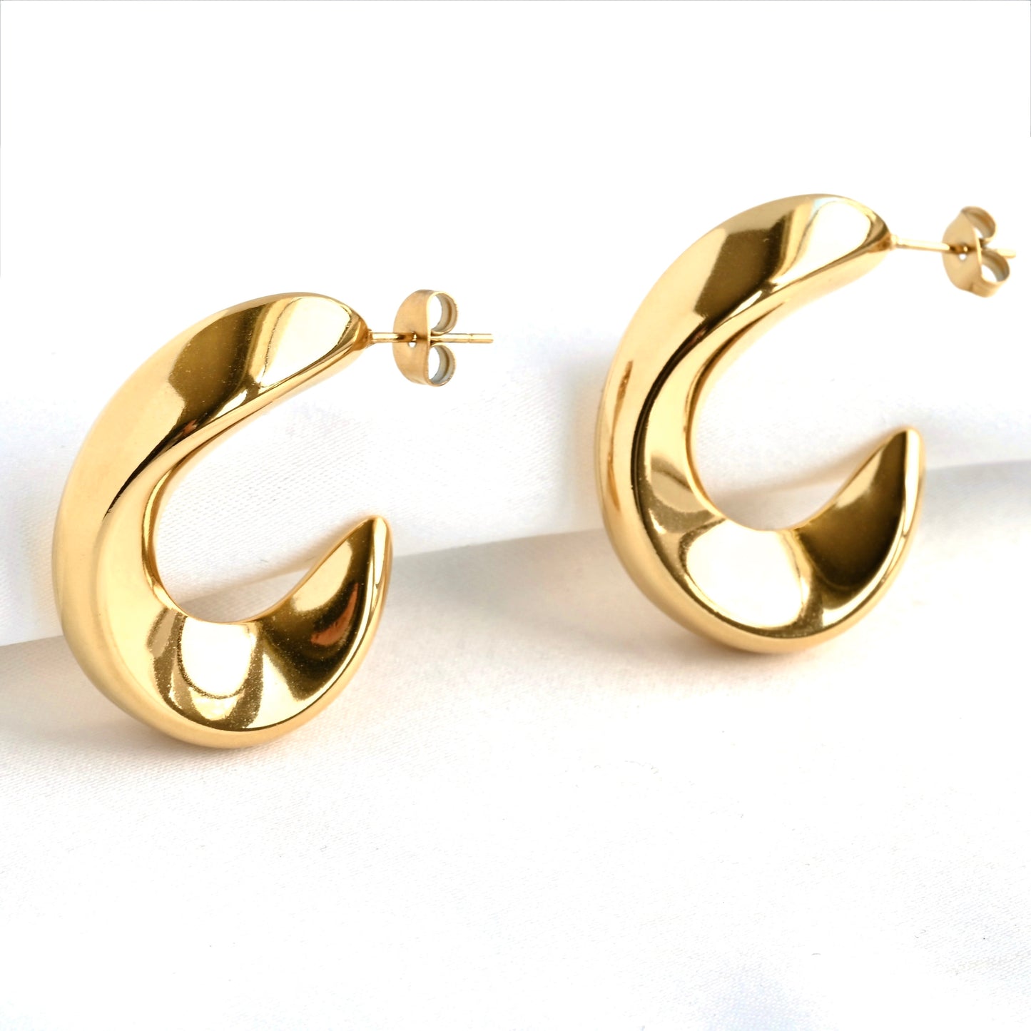 Gold molten hoop earrings on a white background