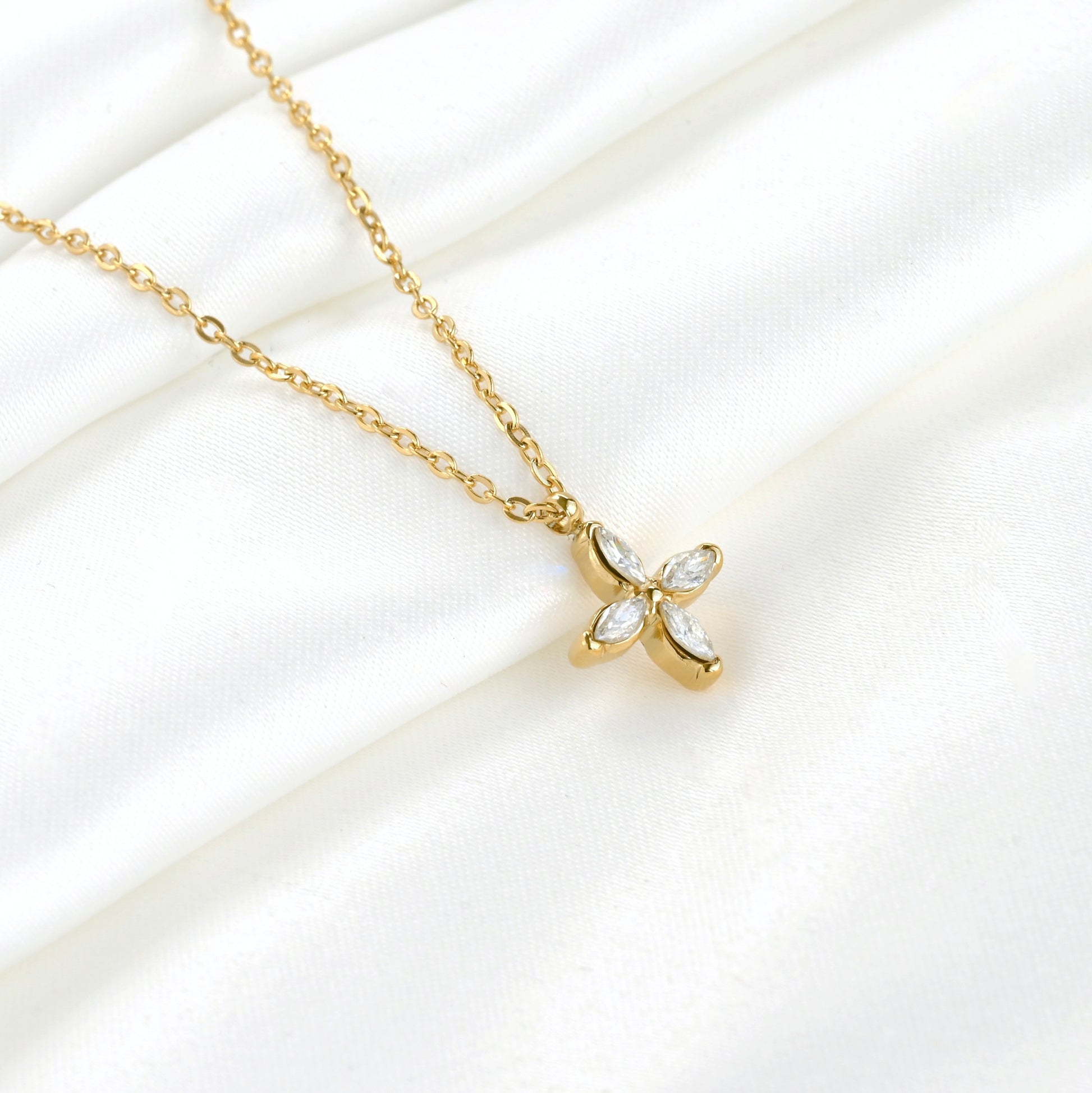 Gold necklace with a diamond clover pendant on a white background