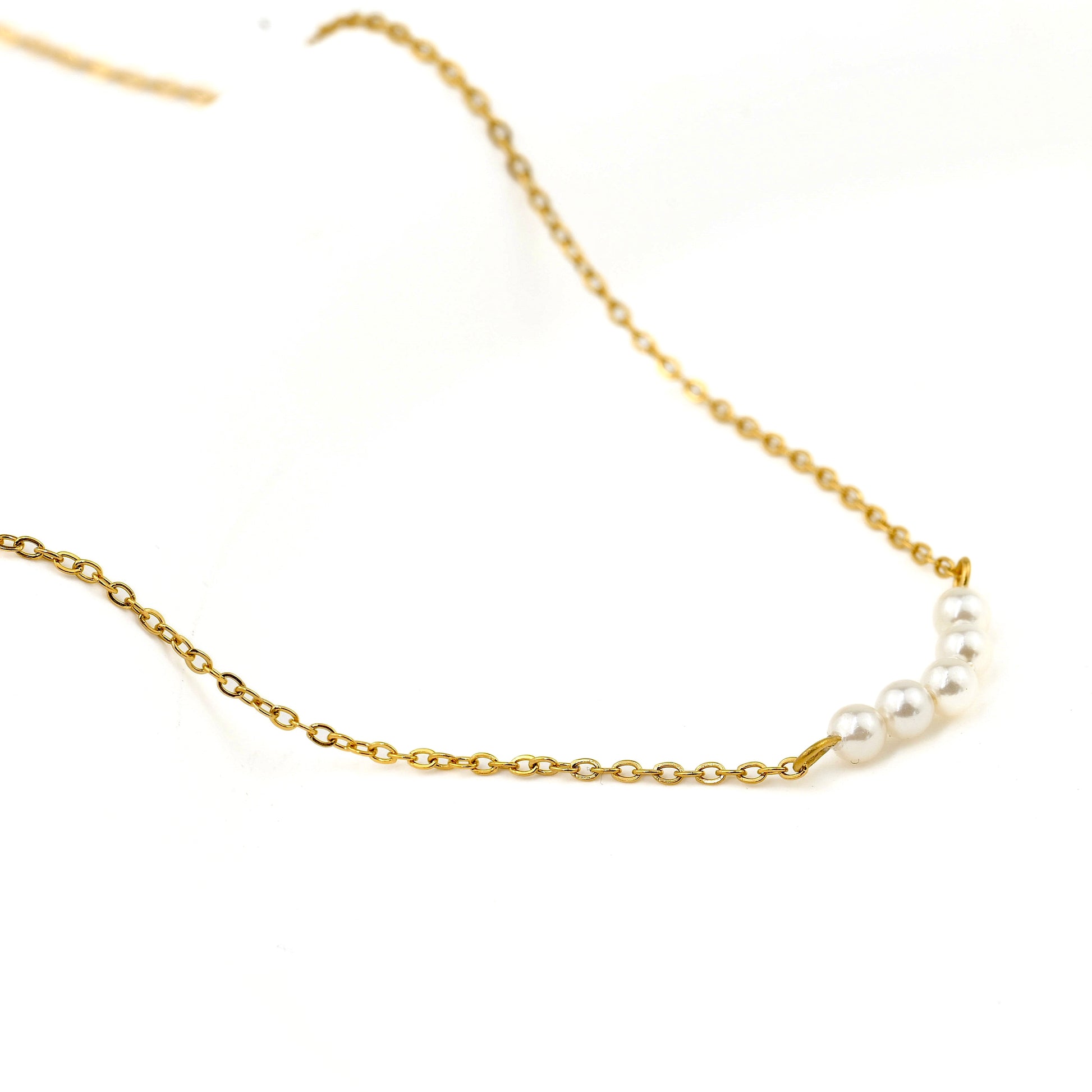 Gold cable chain necklace with pearls on a white background
