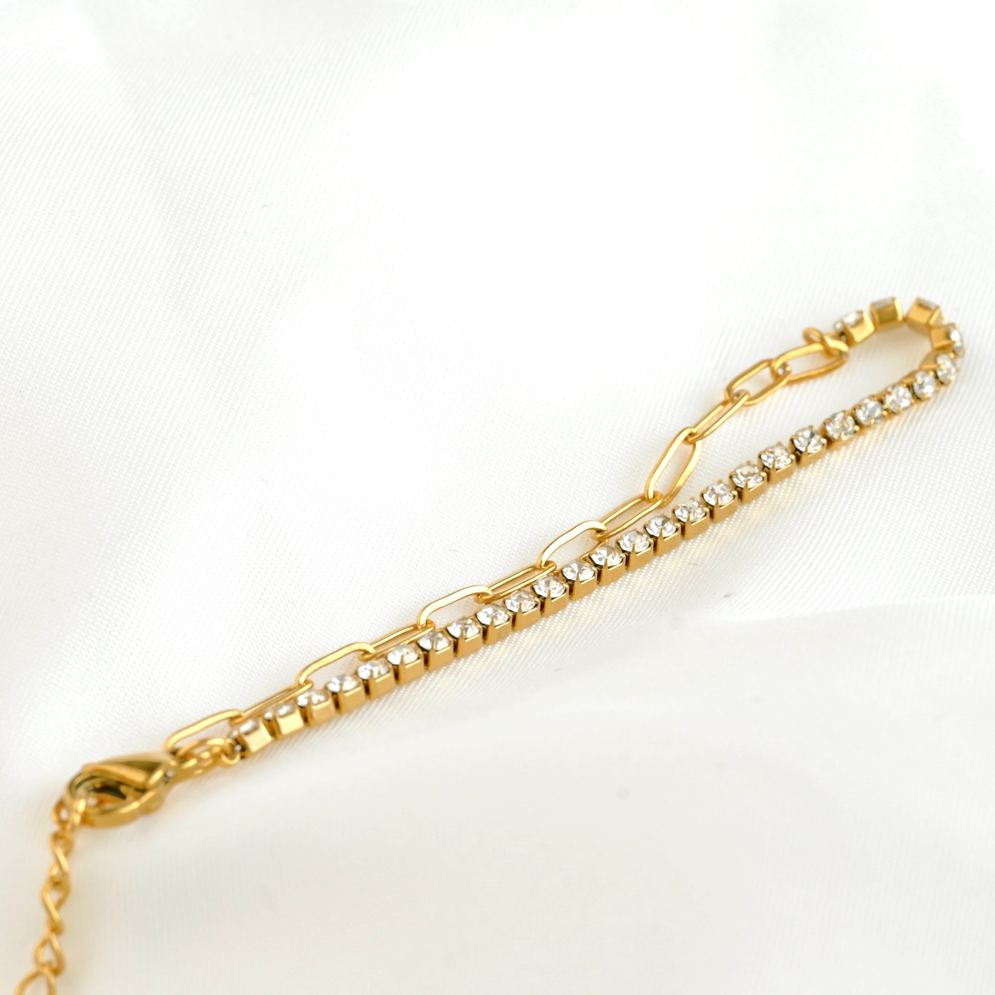 Half paperclip half tennis bracelet with clear stones on a white background