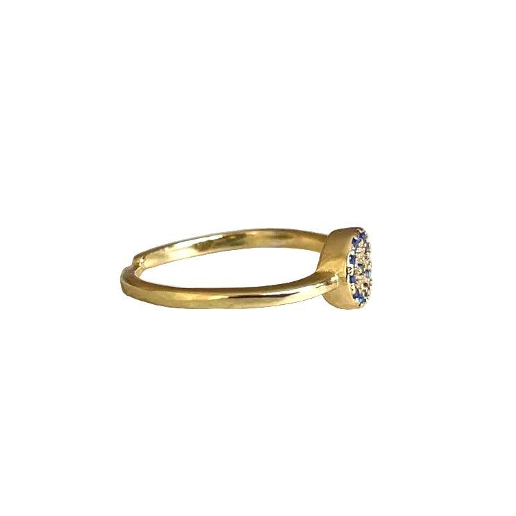 Side view of gold ring with an open back and embedded blue & clear CZ on a white background