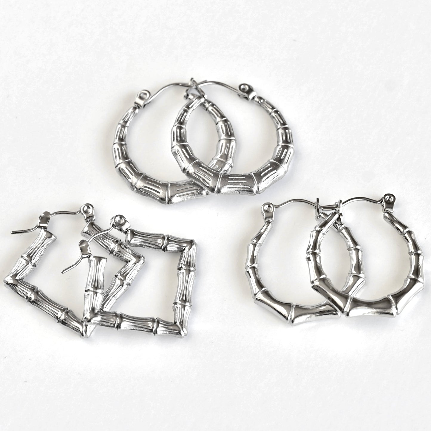 Three pairs of silver-toned hoop earrings with a bamboo branch link design, arranged on a plain white background.