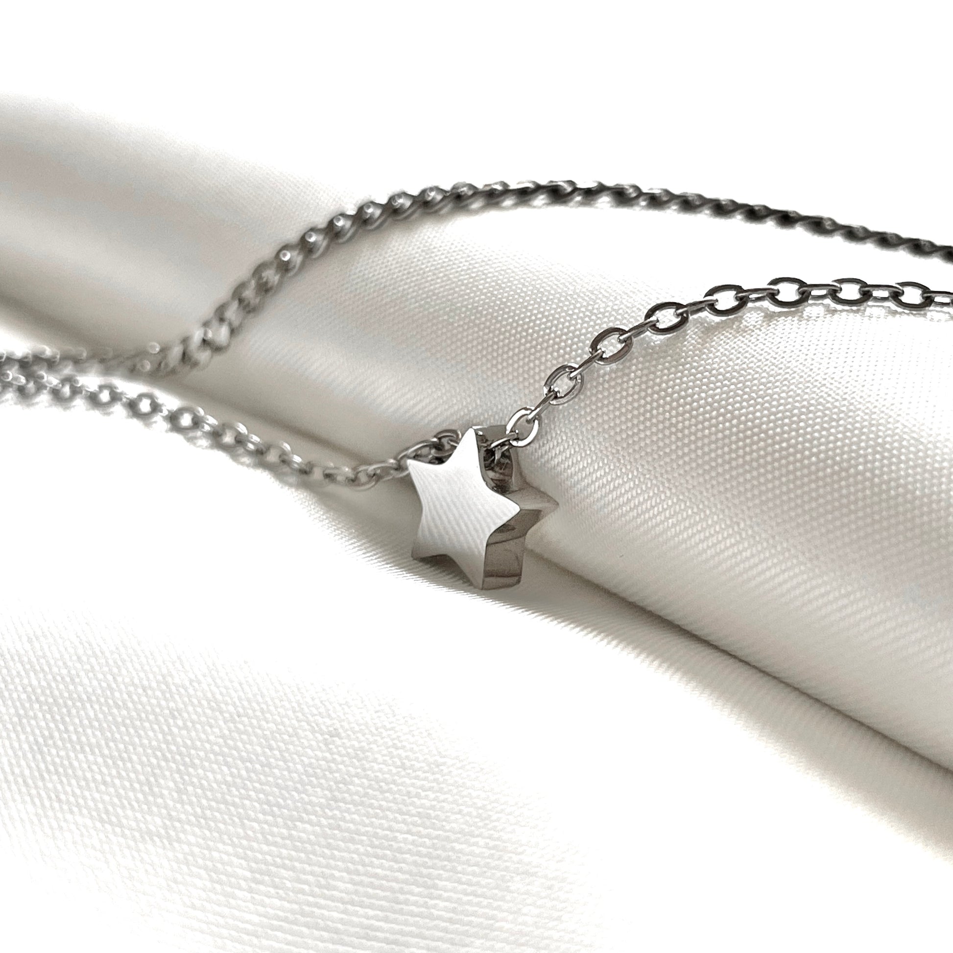 Silver star ankle bracelet on a white fabric background
