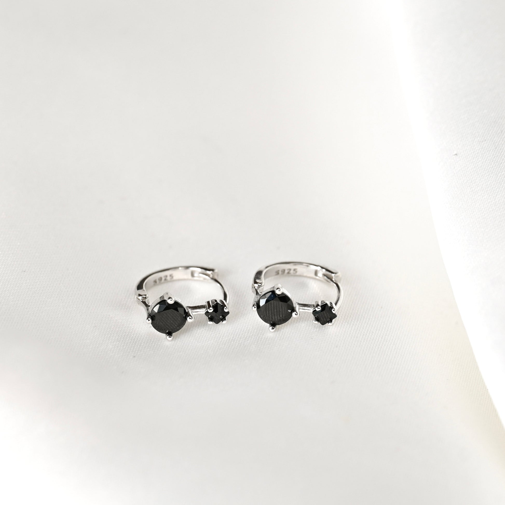 Pair of silver earrings with black gemstones with s925 on a white background