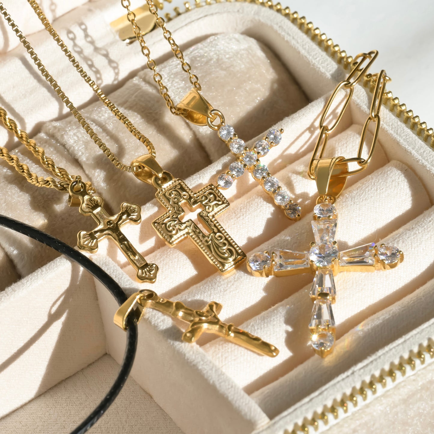 Vintage gold cross necklaces with clear stones under direct sunlight.