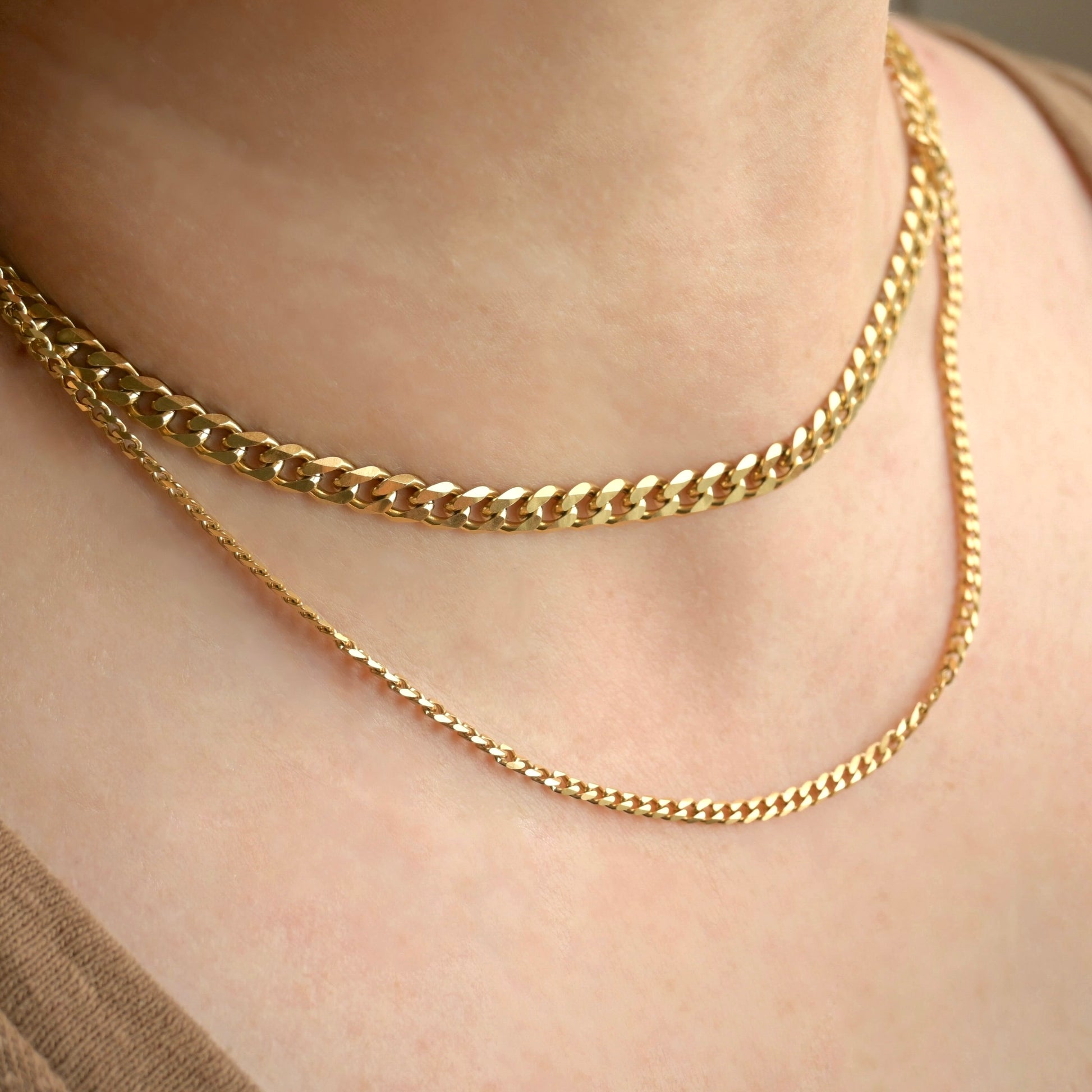 Two Gold cuban link chains layered on a person's neck