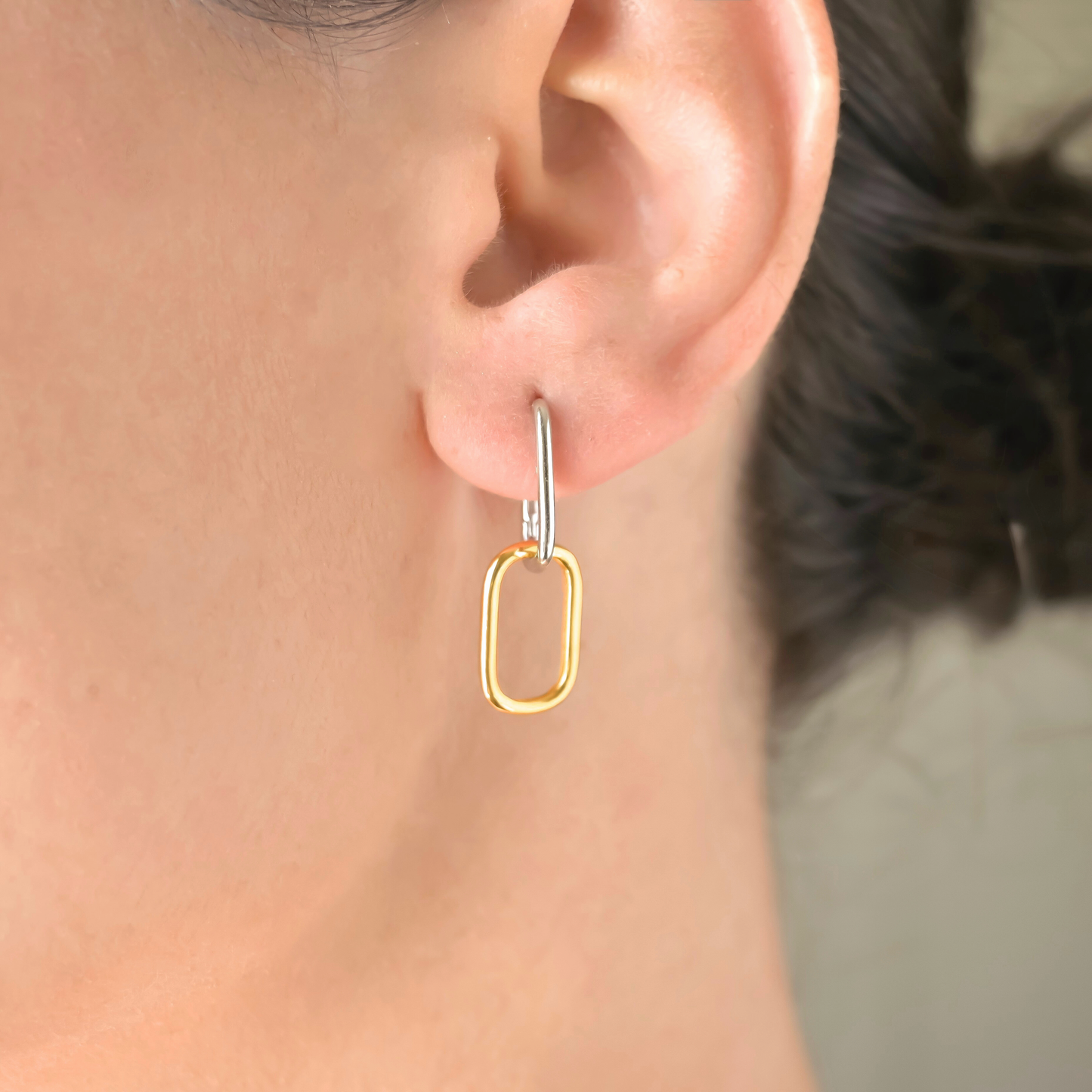 Two-tone U shaped double hoop earring worn by a person with a blurred background