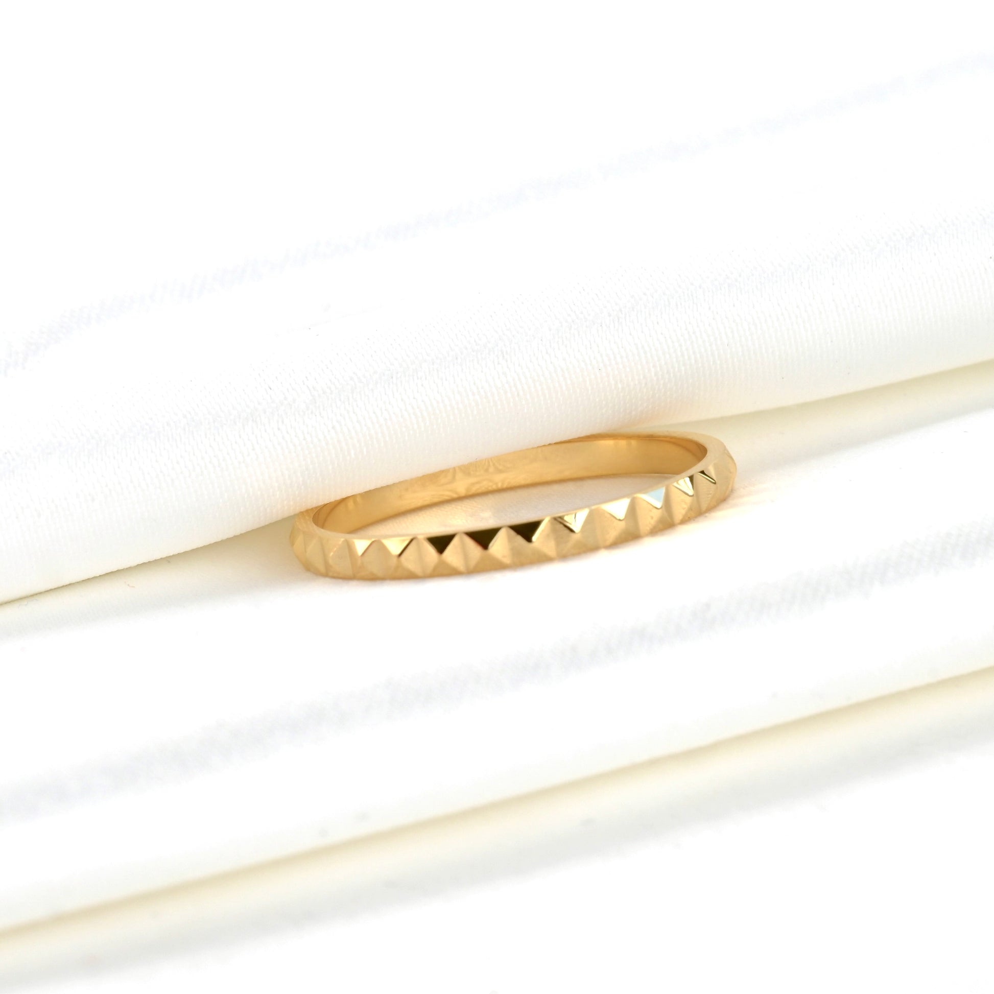 Gold pyramid ring with a textured band on a white background