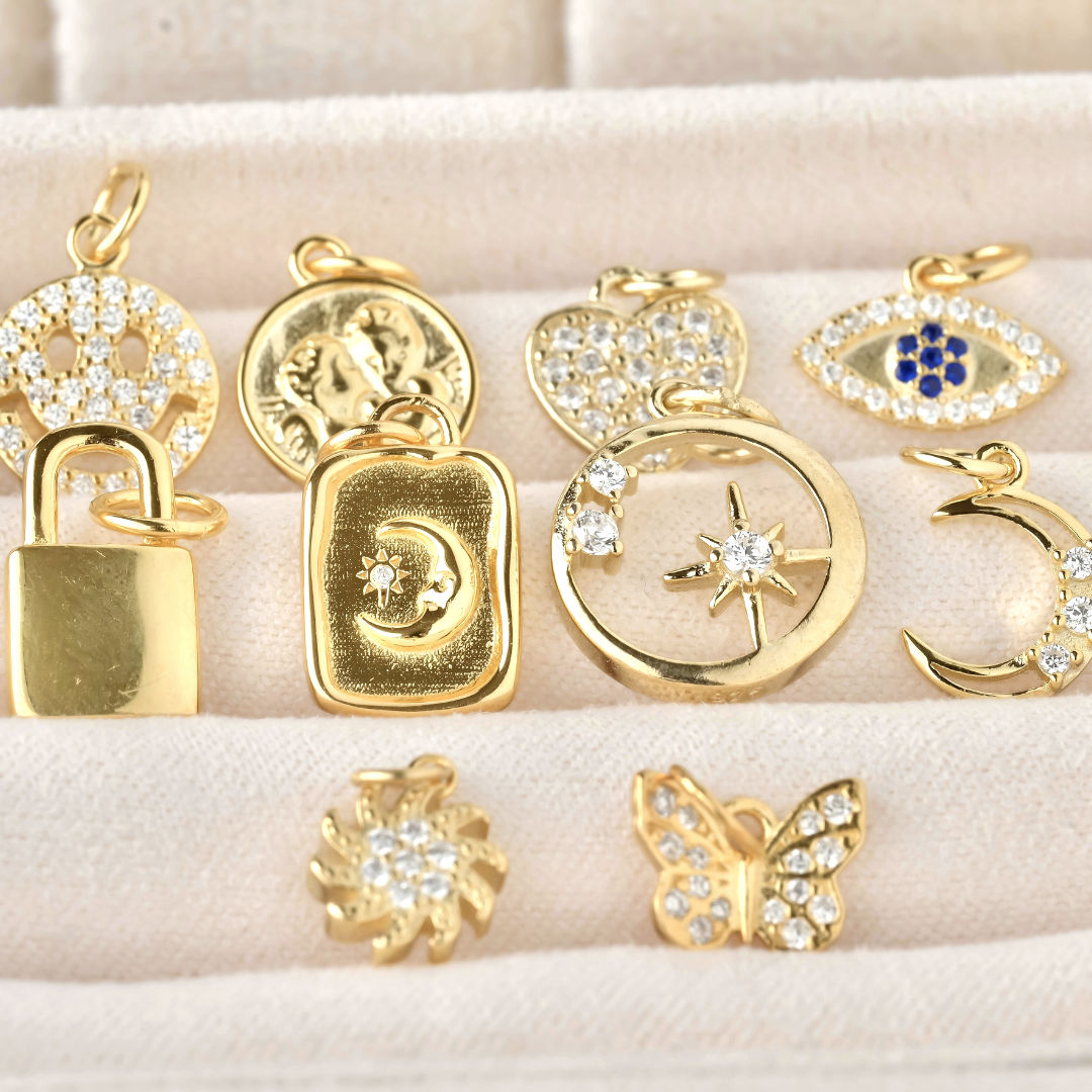Top view: collection of gold pendants on a beige surface