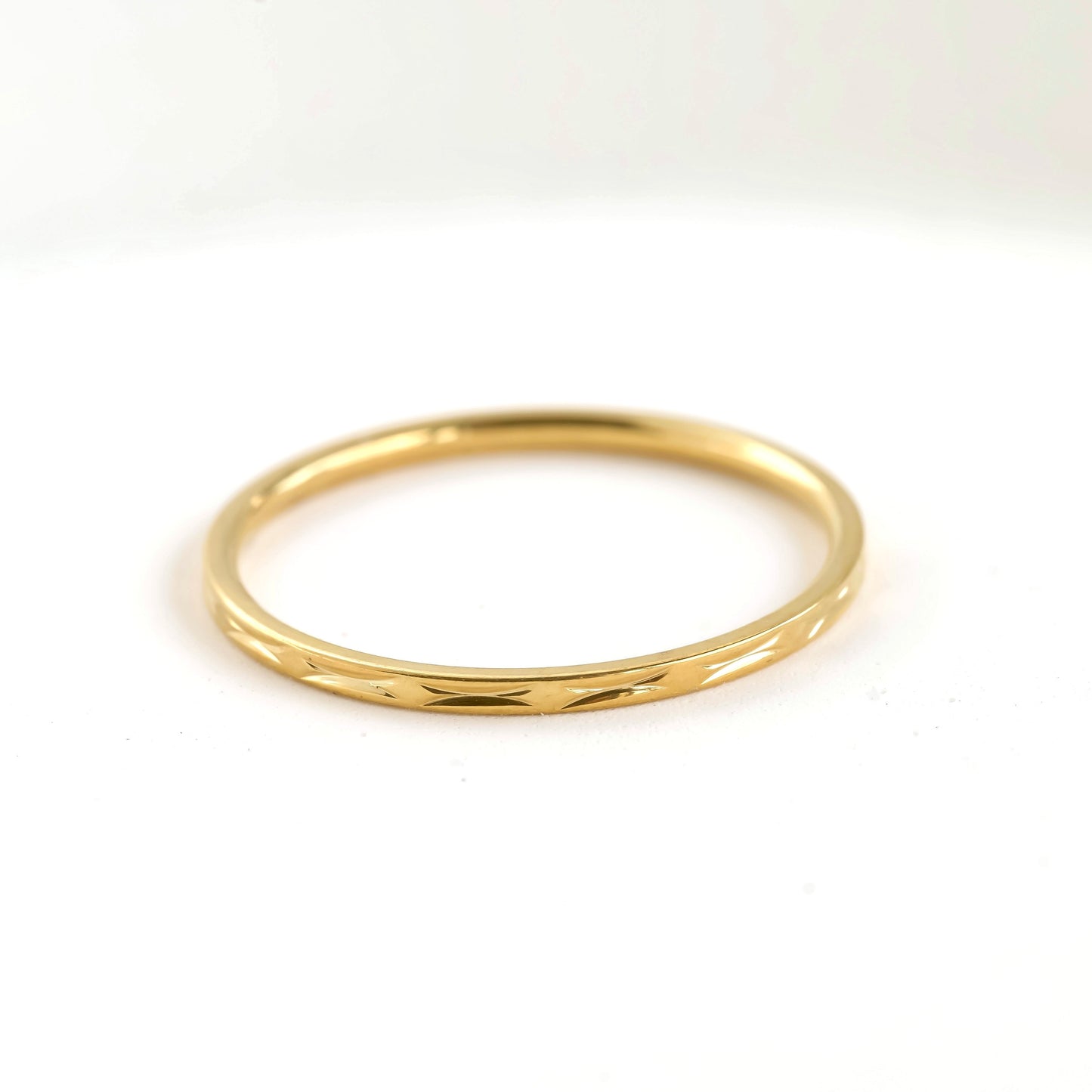 Textured dainty thin gold ring on a white background