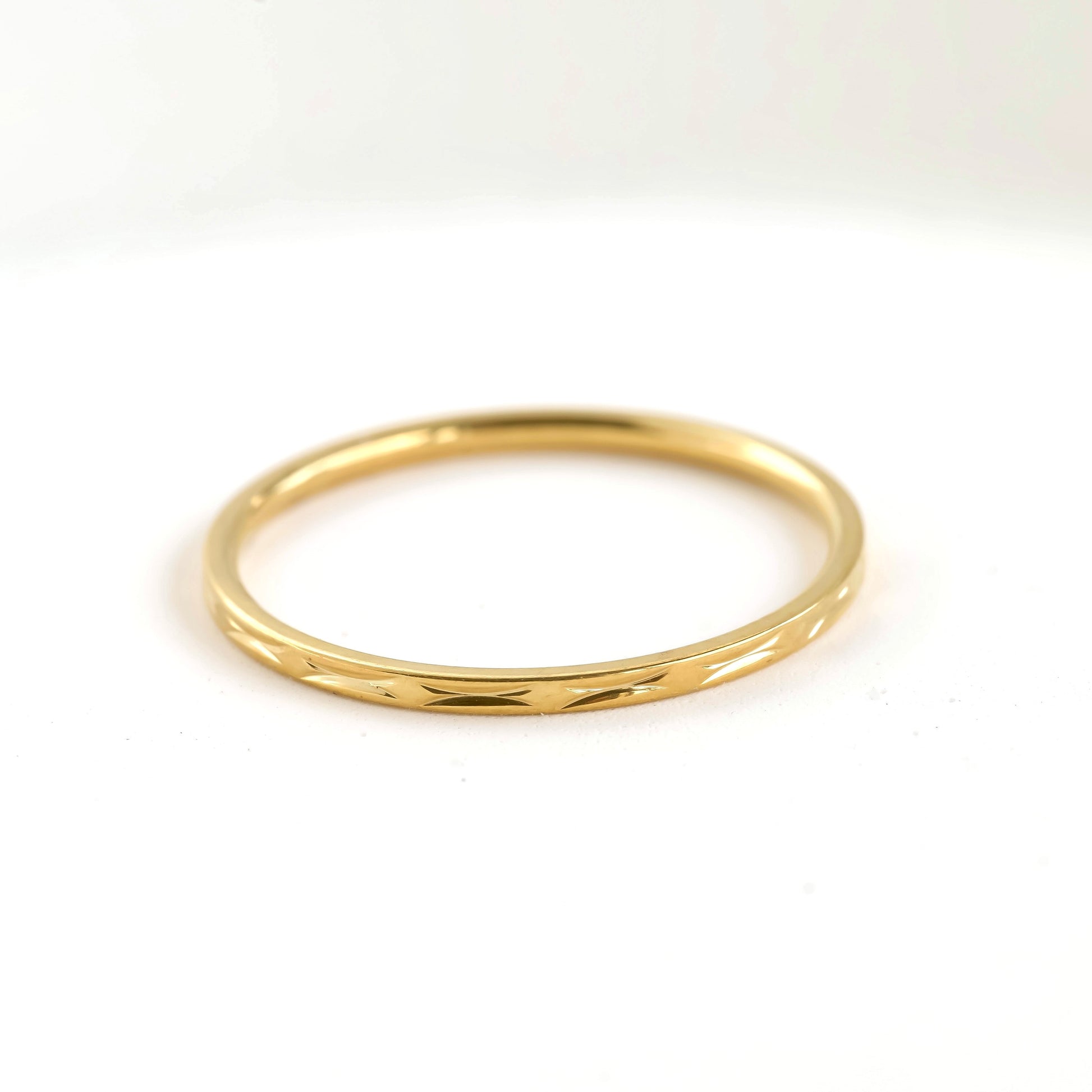 Textured dainty thin gold ring on a white background