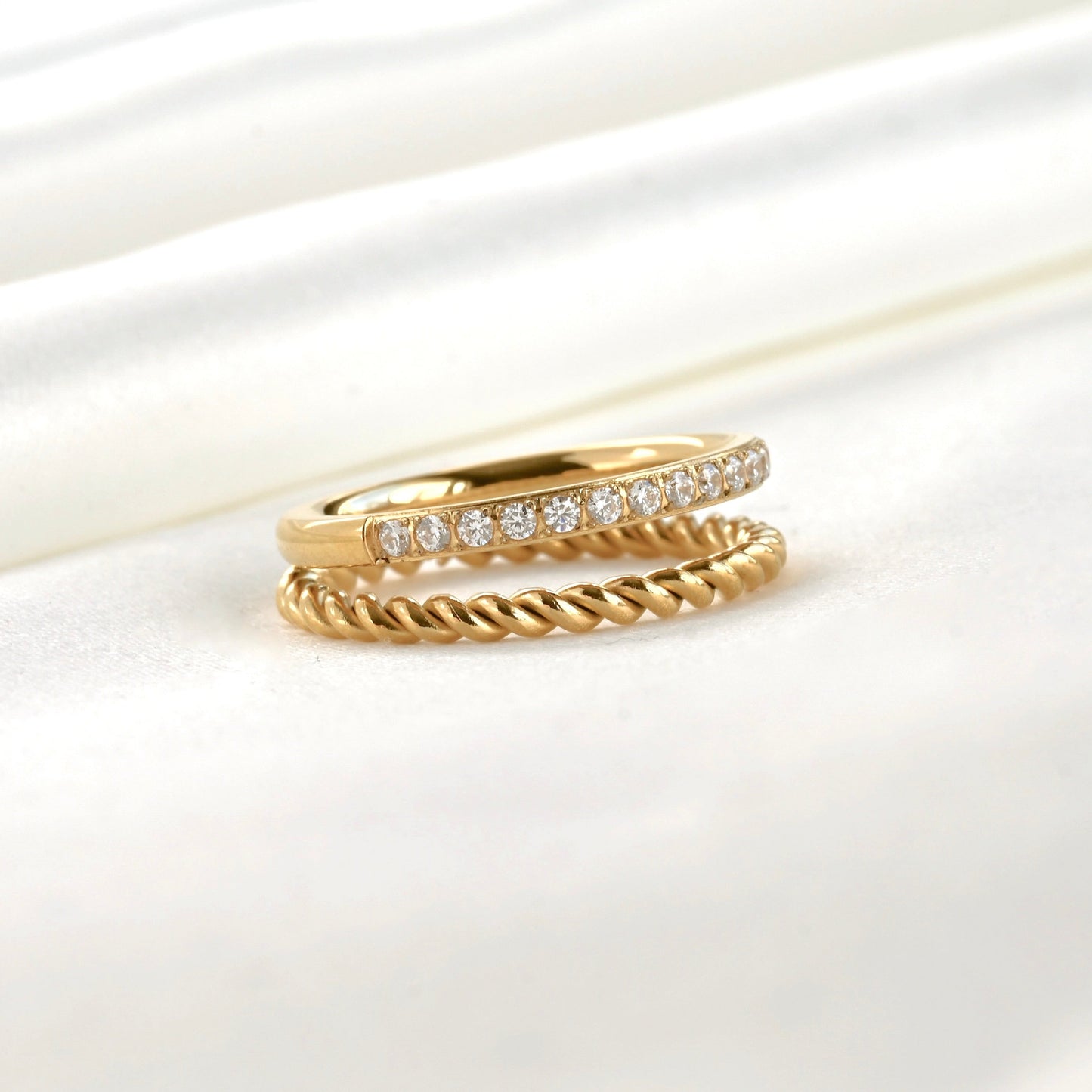 Stacked look layered gold ring with a twisted rope band and a half eternity pave CZ band attached together on a white background