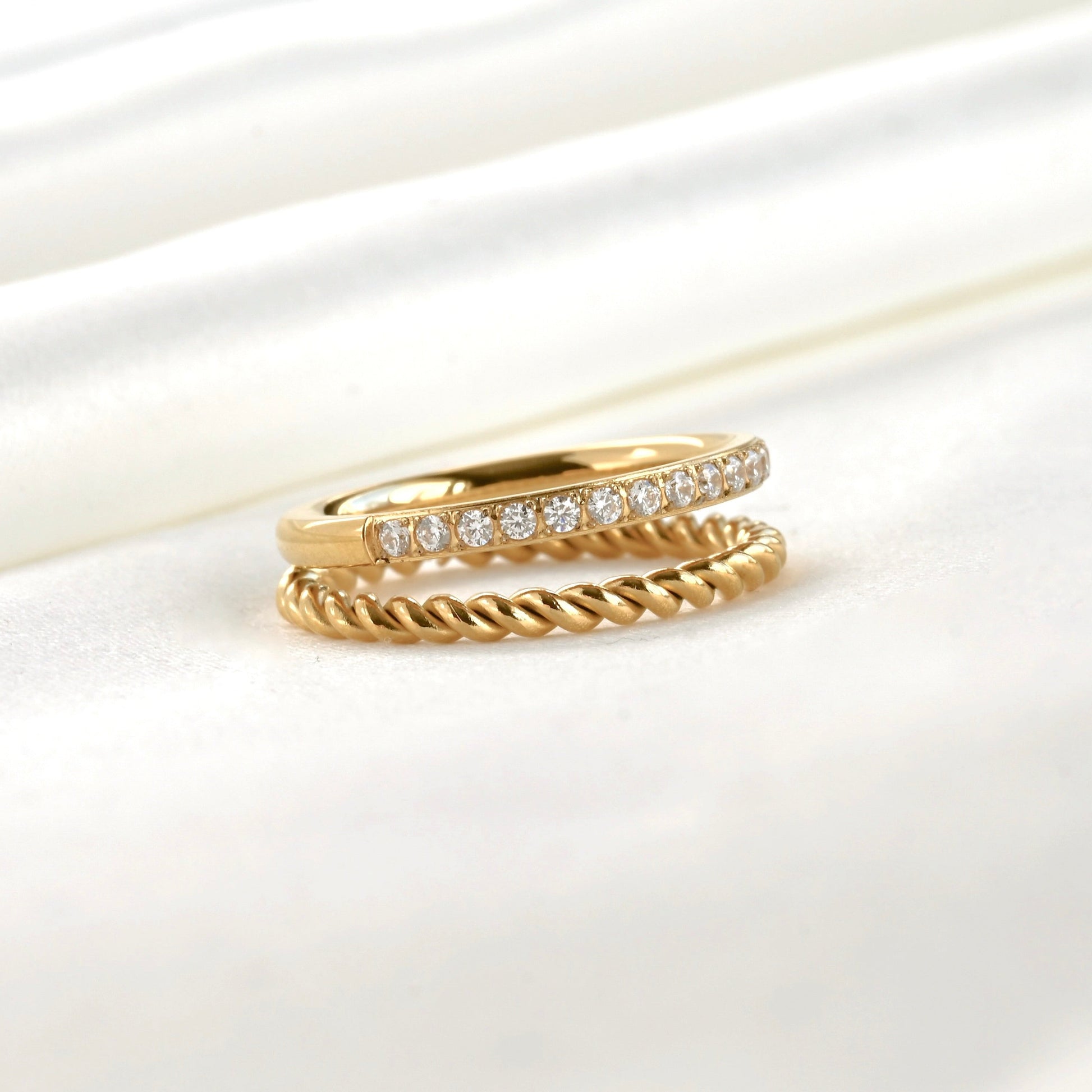 Stacked look layered gold ring with a twisted rope band and a half eternity pave CZ band attached together on a white background