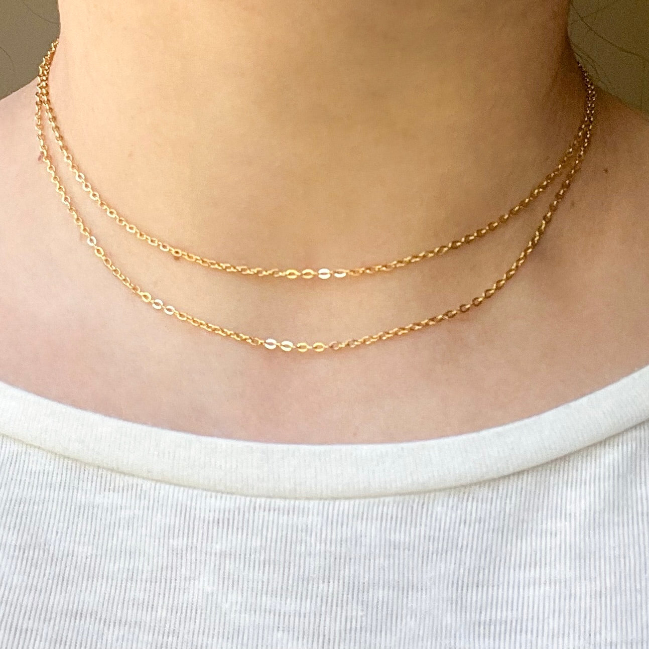Two linked cable chains one 15" and one 16", on a person wearing a white top