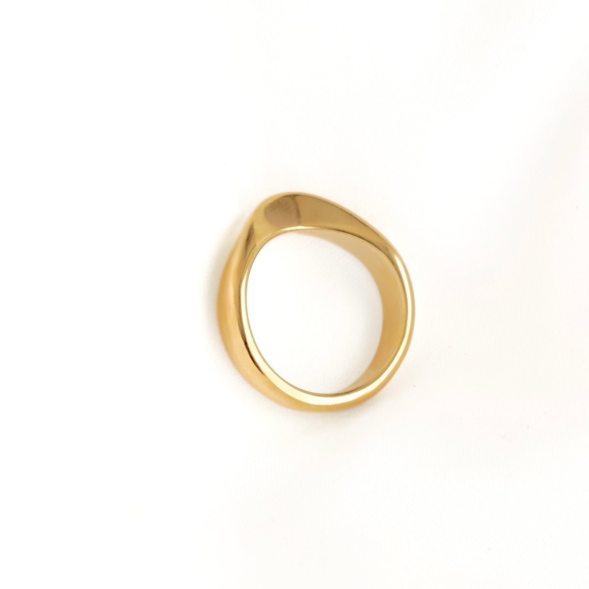 A polished gold ring with a teardrop-shaped, organic silhouette, photographed on a clean white background.