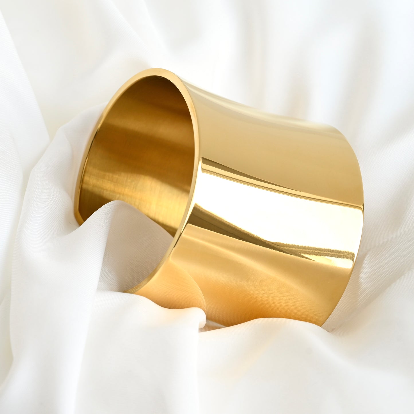 Gold statement cuff bracelet on a white fabric background