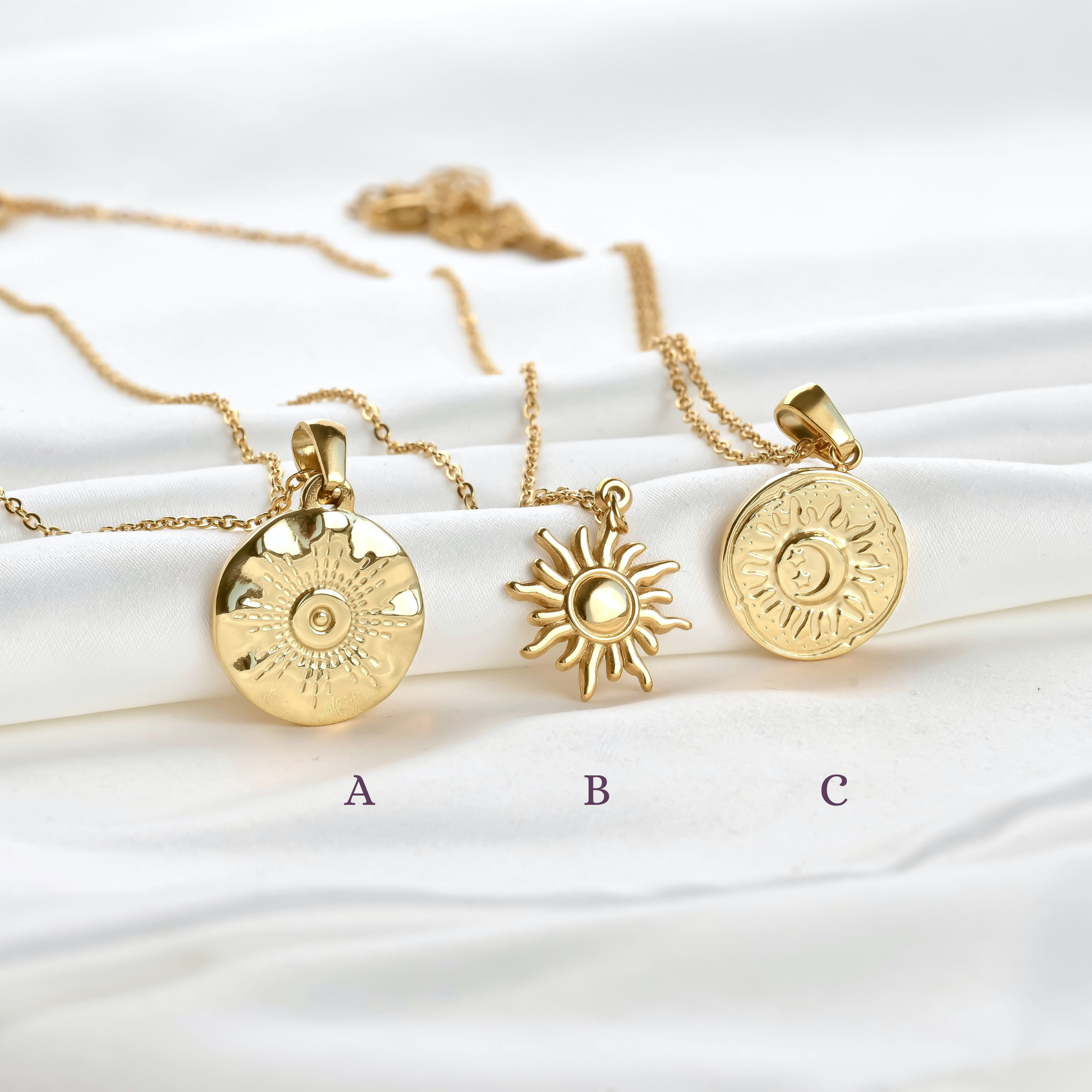 Three gold  necklaces with different sun coin pendants on a white background