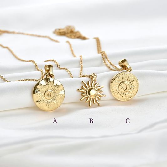 Three gold  necklaces with different sun coin pendants on a white background