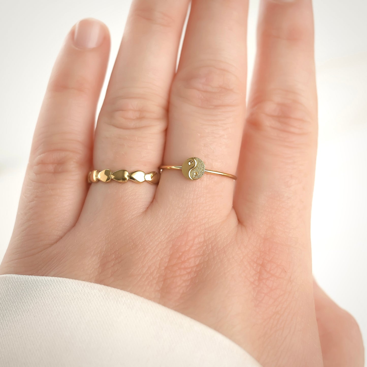 Textured yin and yang charm ring on a finger against a white background