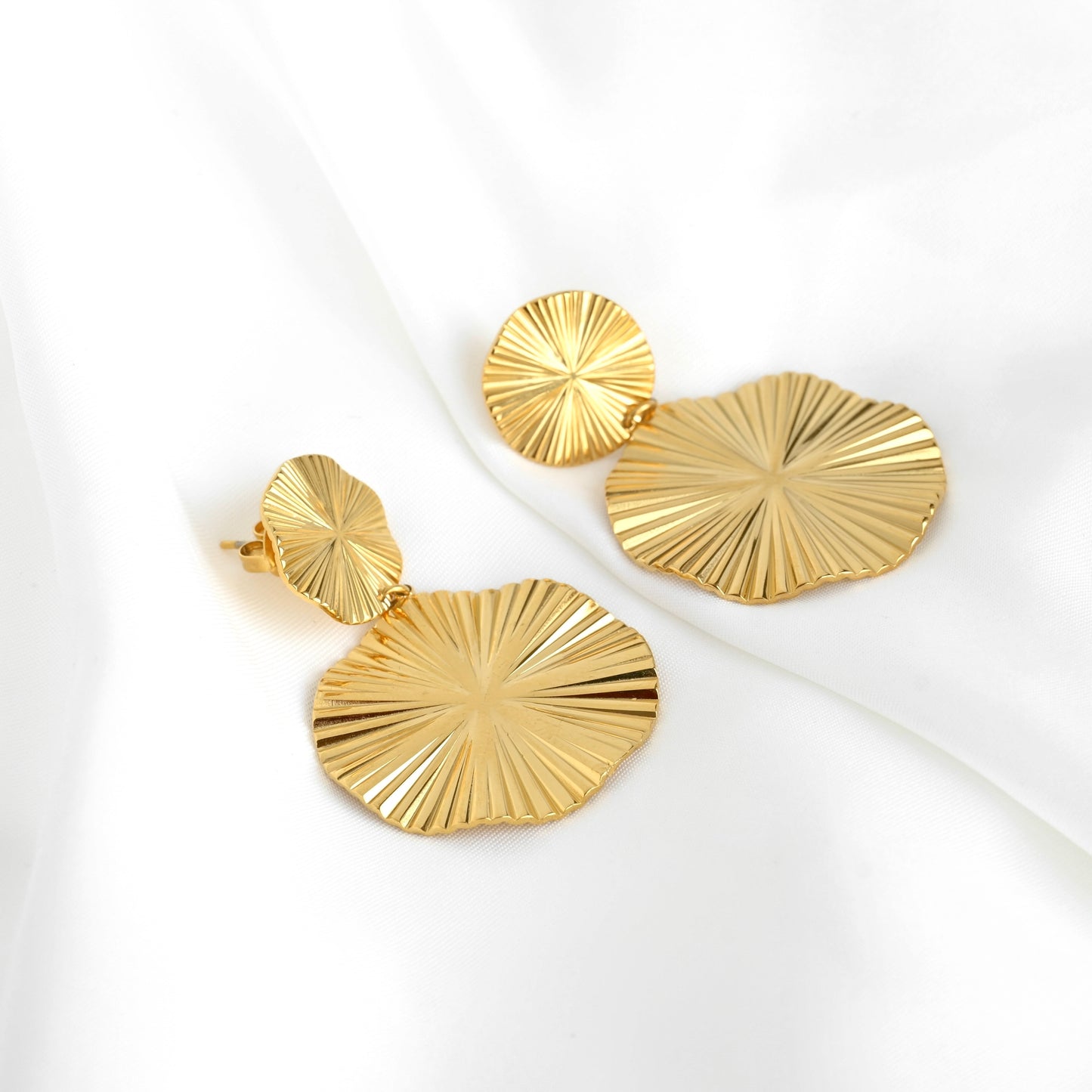Pair of round gold dangle earrings on a white background