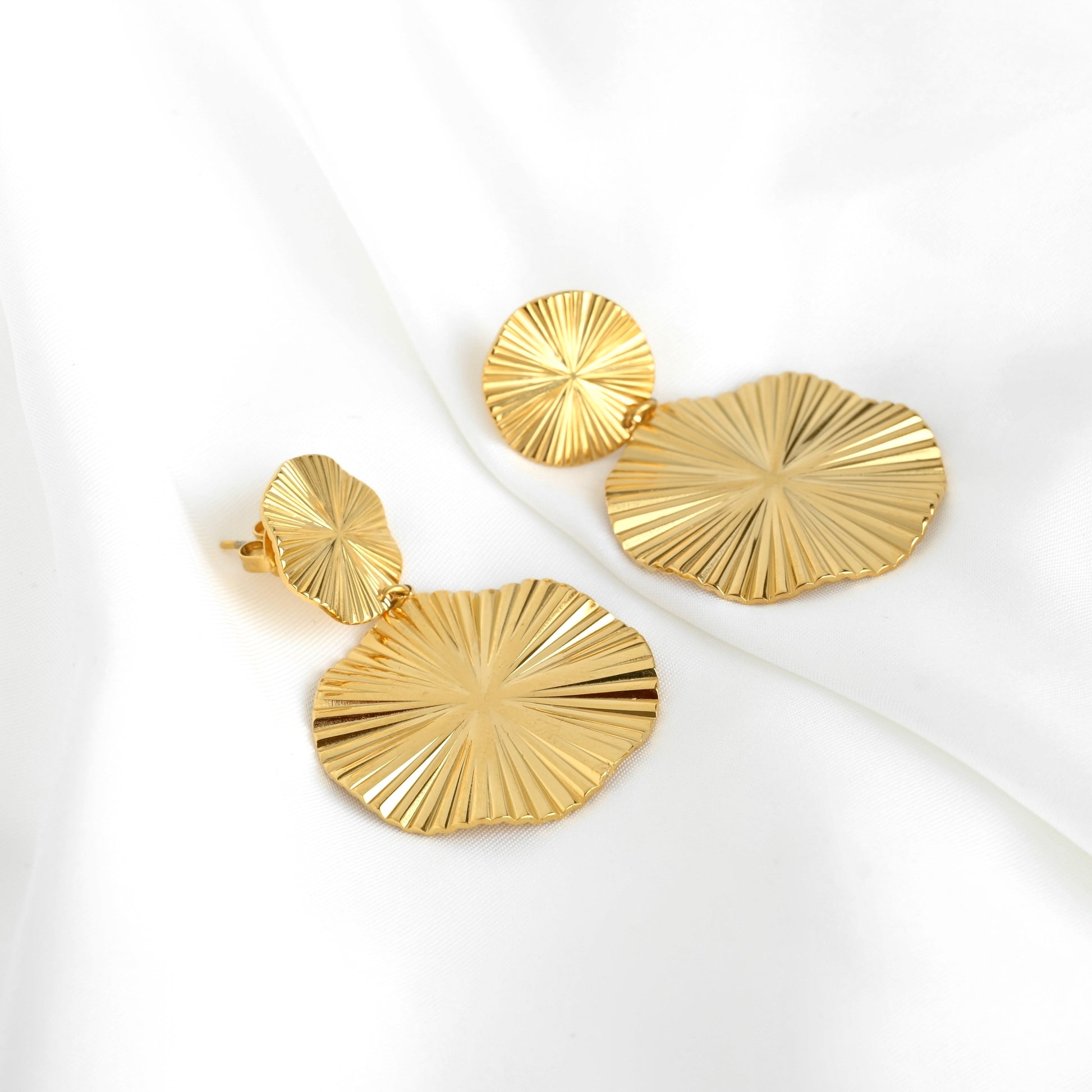 Pair of round gold dangle earrings on a white background