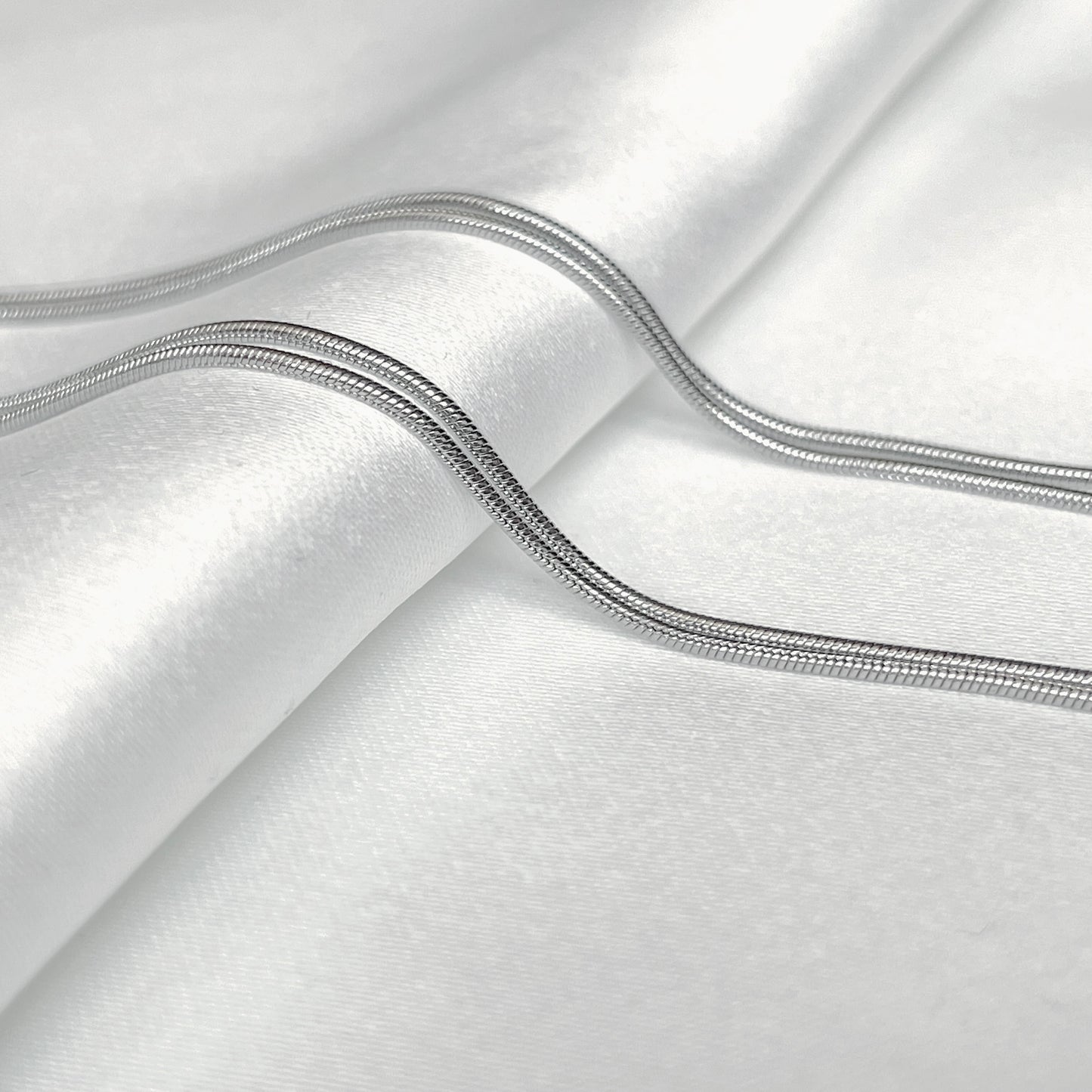 Close-up of silver snake chain on a white background