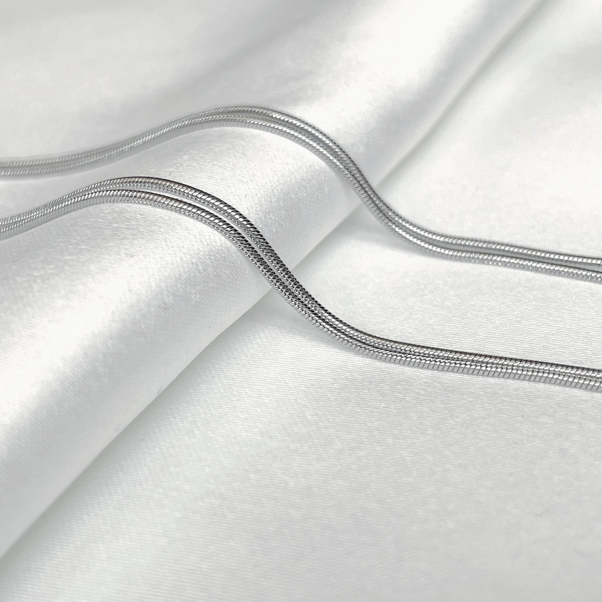 Close-up of silver snake chain on a white background
