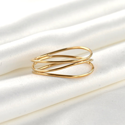 Gold ring with three wavy intertwined bands on a white fabric background