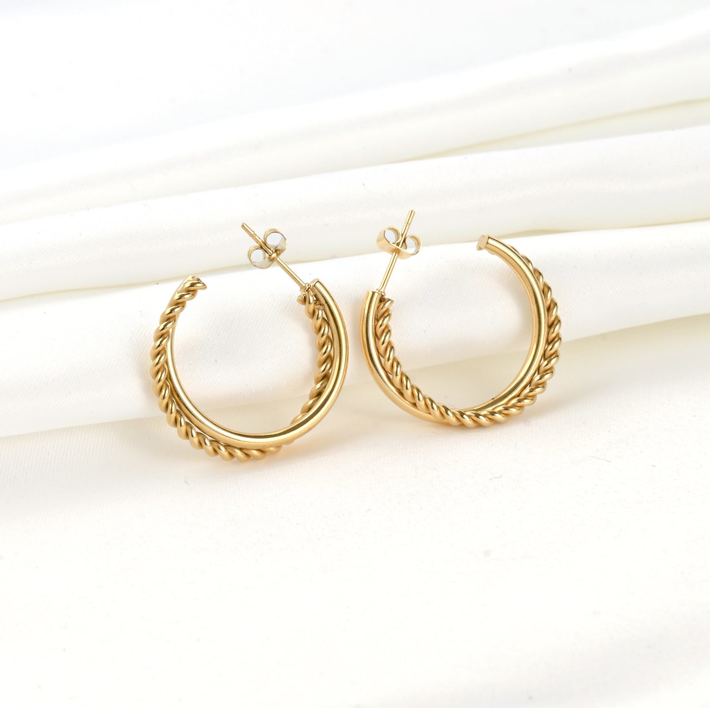 Mixed texture thin gold C hoop earrings on a light background