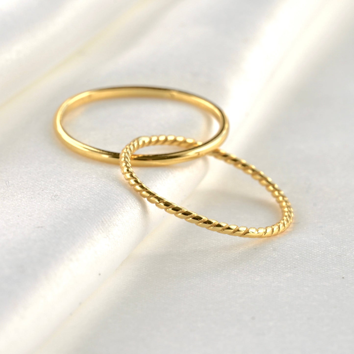 Gold interlocking bands ring on a light gray surface