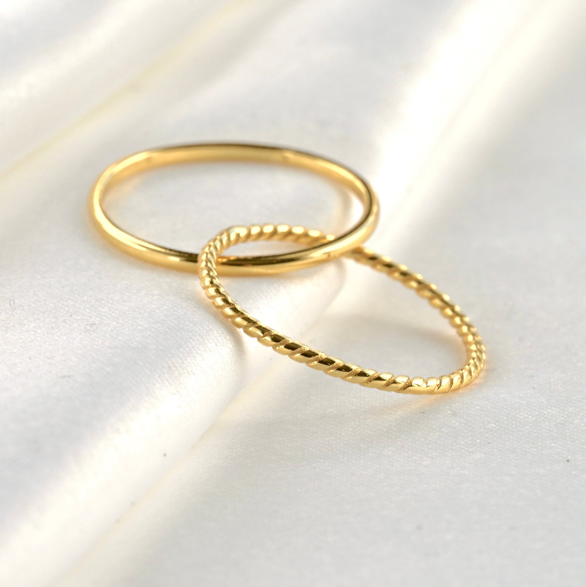Gold interlocking bands ring on a light gray surface