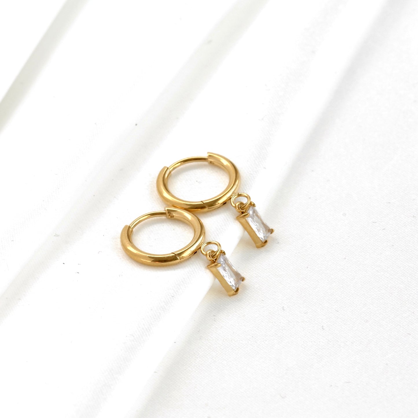 Wide angle view of Gold rectangular stone  drop hoop earrings on a white background