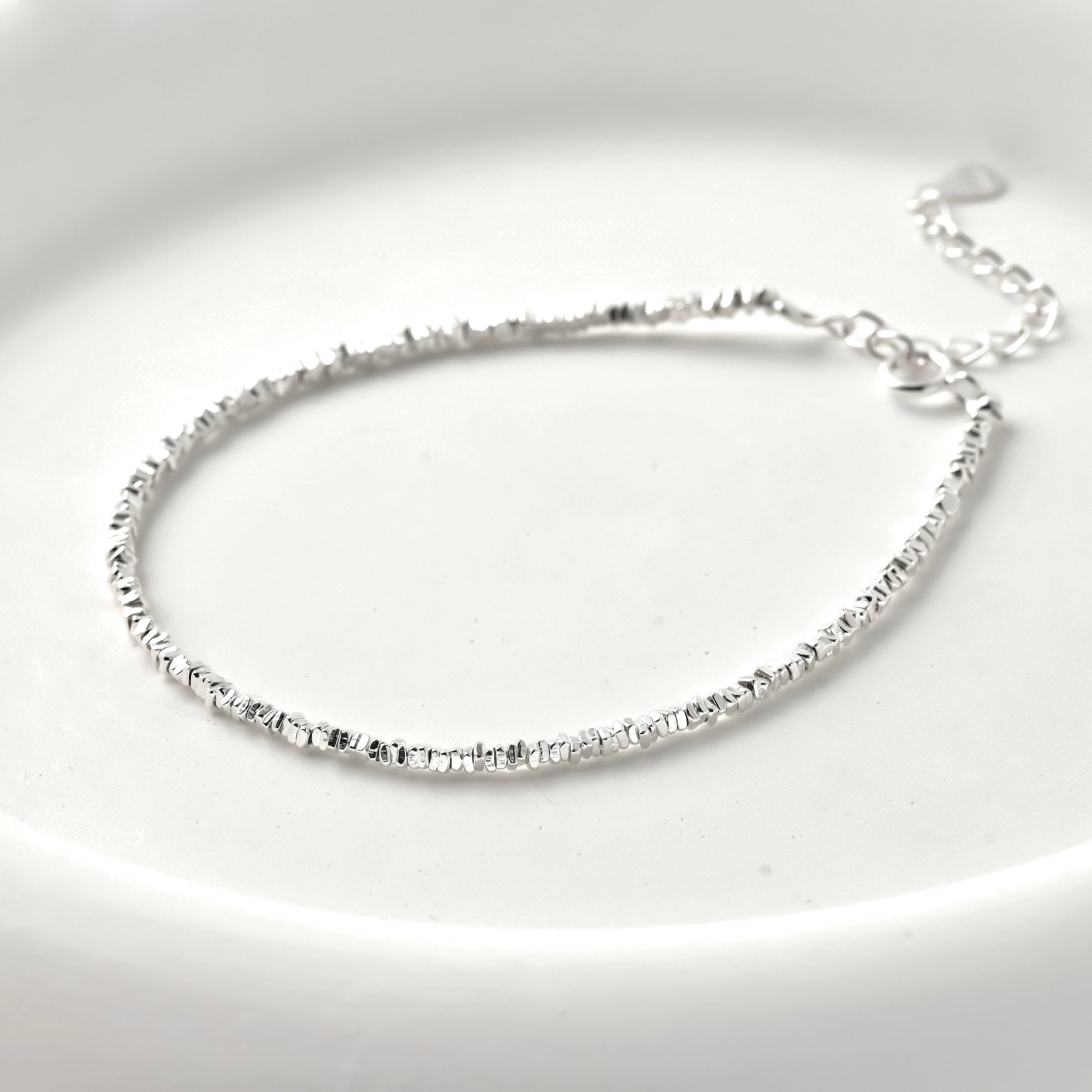 Silver square beaded bracelet  on a light gray background