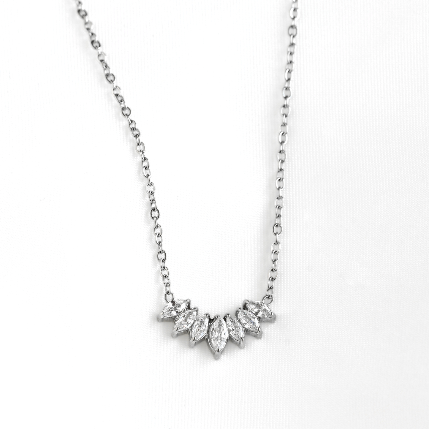 A silver-toned necklace featuring a curved cluster of marquise-cut clear gemstones on a delicate chain, displayed against a clean white background.
