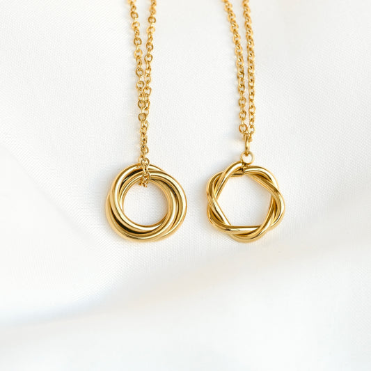 Two gold necklaces with twisted circular pendants on a white background